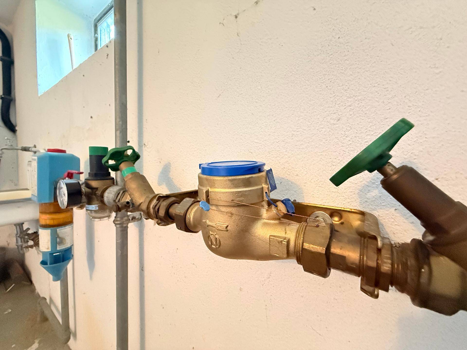 Detailansicht der Wasserleitungen und Zähler im Kellerbereich des Hauses.