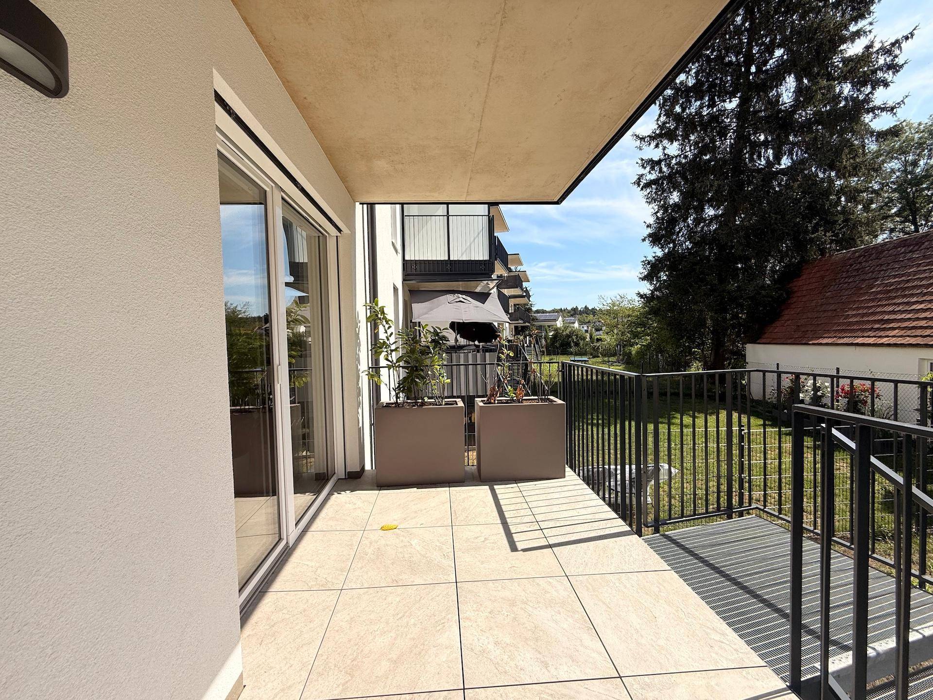 Geräumiger Balkon mit Fliesenboden und Blick ins Grüne, ideal zum Entspannen.