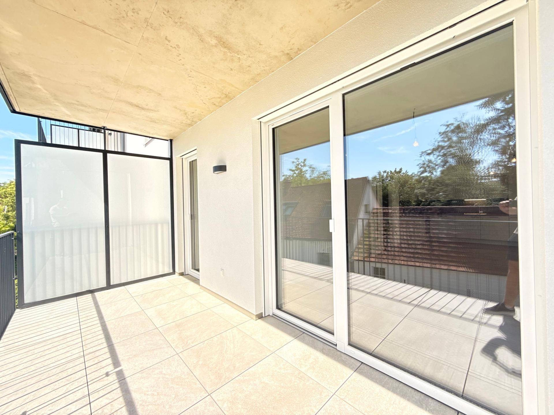Heller Balkon mit Schiebetür zum Innenbereich und viel Sonnenlicht.