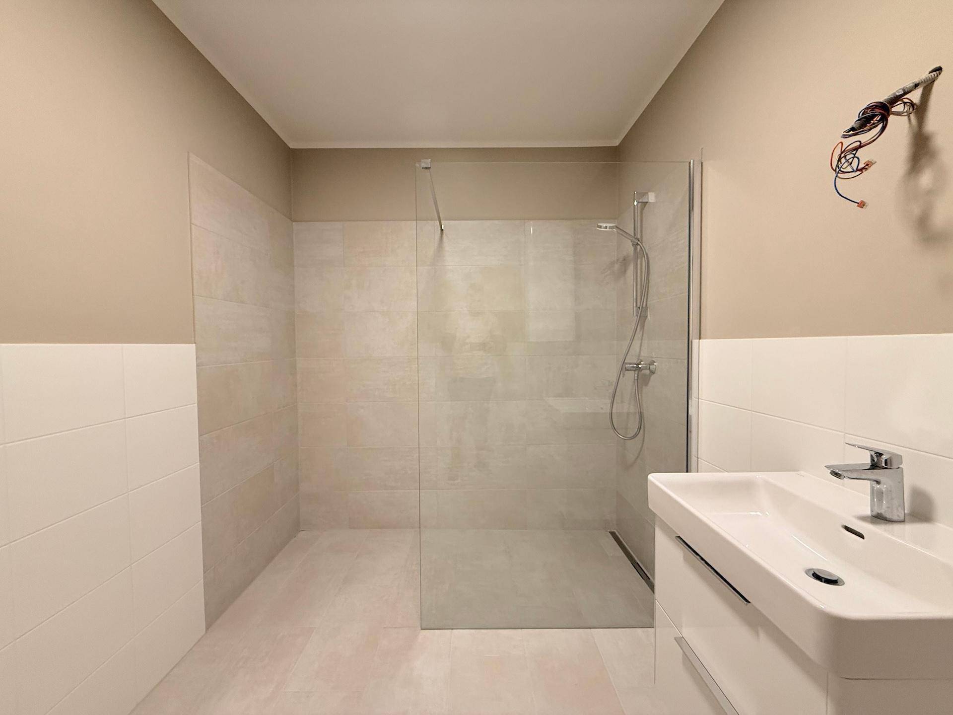Helles Badezimmer mit großer, begehbarer Dusche und modernem Waschbecken.
