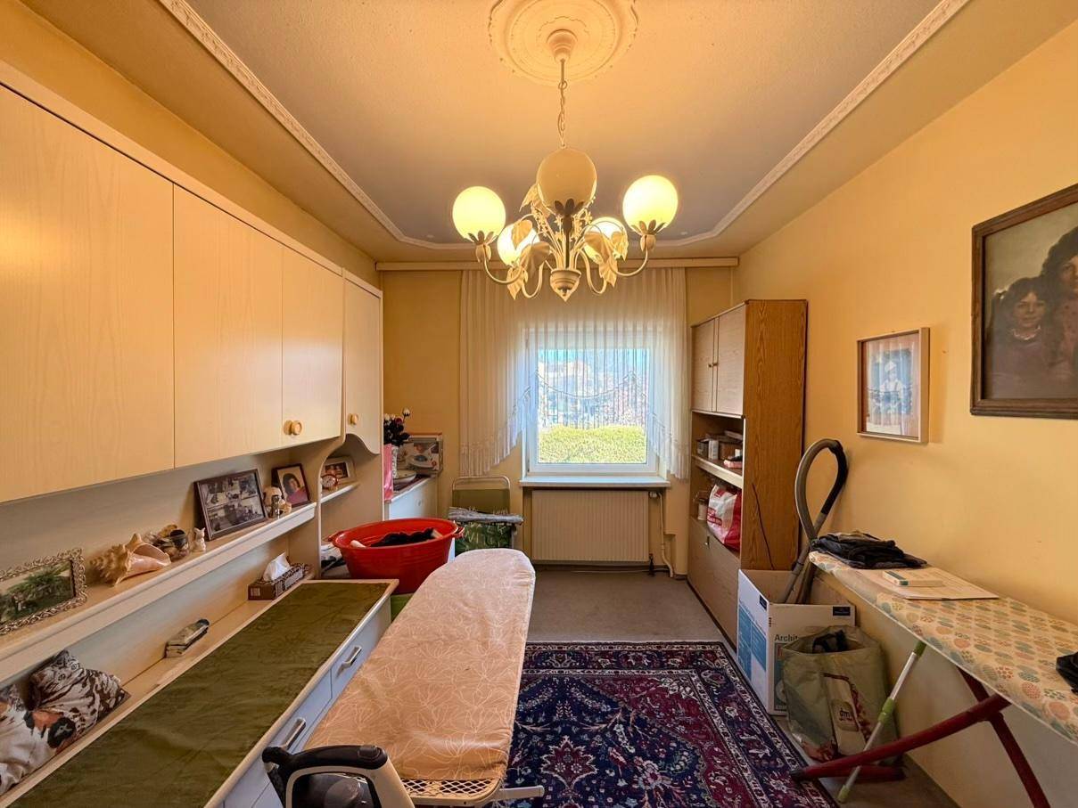 Hauswirtschaftsraum mit Einbauschränken, Bügelbrett und einem Fenster, das für Helligkeit sorgt.