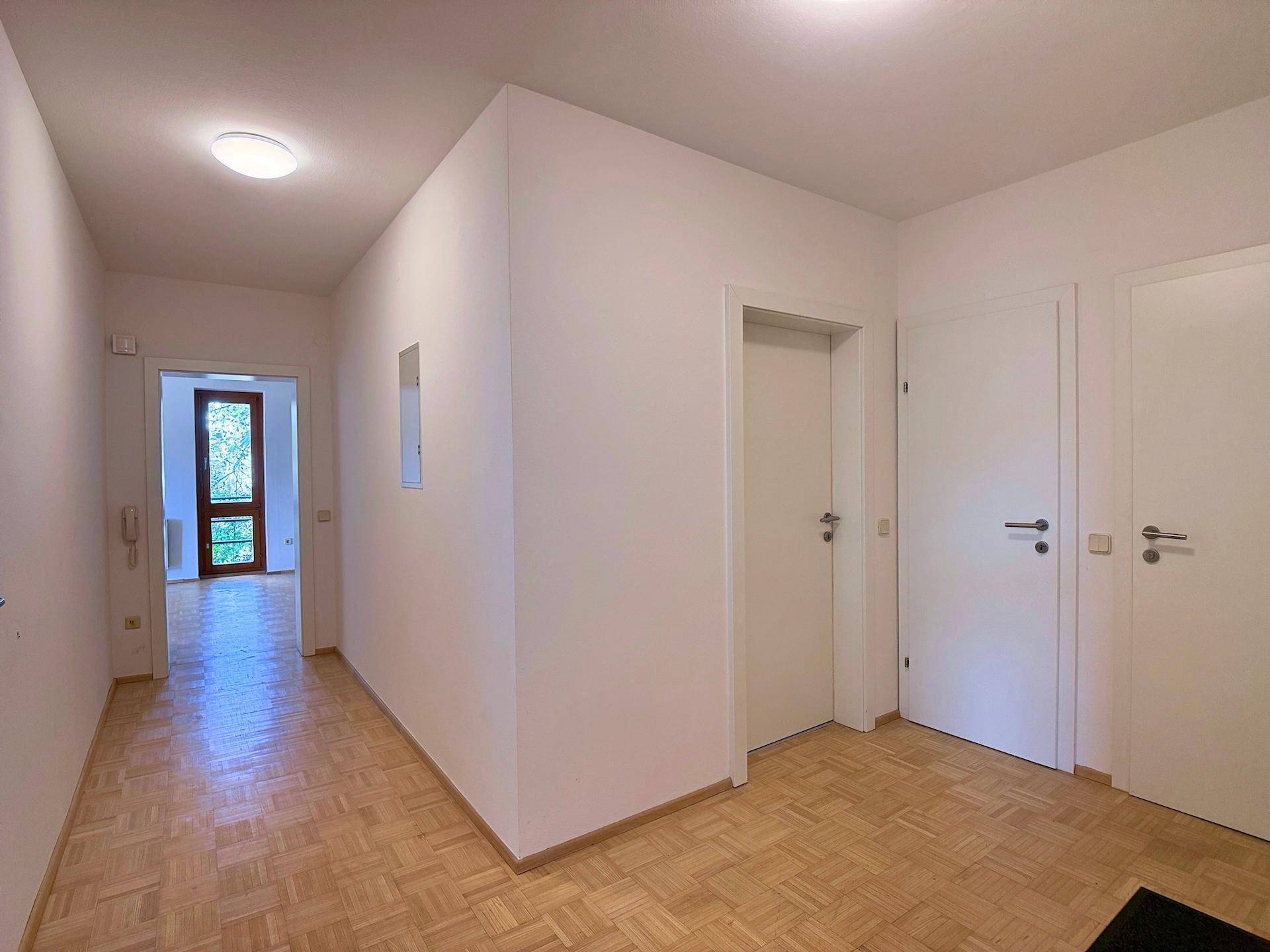 Freundlicher Eingangsbereich mit Parkettboden und Zugang zu verschiedenen Zimmern der Wohnung.