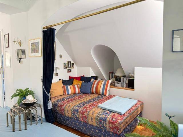 Gemütlicher Schlafbereich unter einer Dachschräge mit Tagesbett und bunten Kissen.