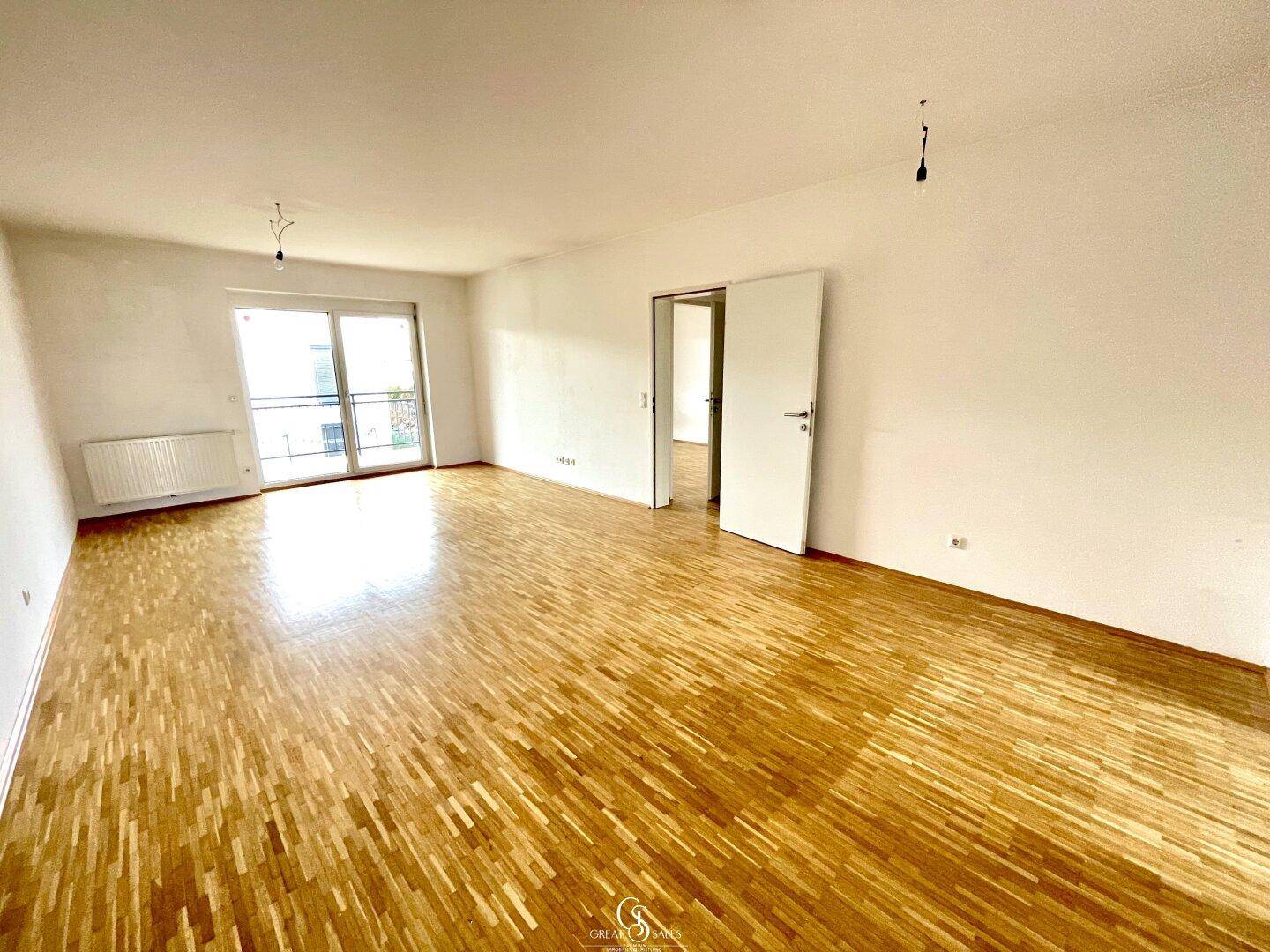 Helles Wohnzimmer mit Parkettboden und Zugang zu einem Balkon, bereit zur individuellen Gestaltung.