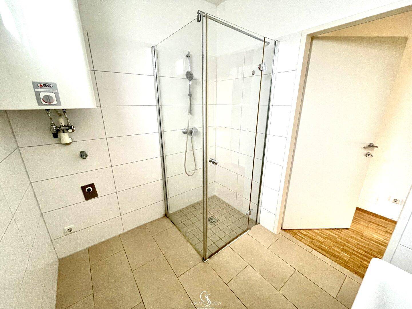 Helles Badezimmer mit Duschkabine, weißen Fliesen und Heizkörper, funktional und sauber.