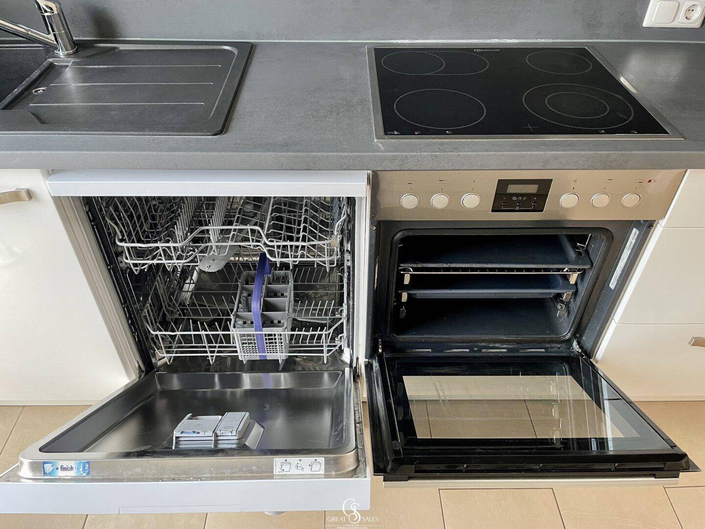 Detailansicht der Küche mit geöffnetem Geschirrspüler und Backofen, bereit zur Nutzung.