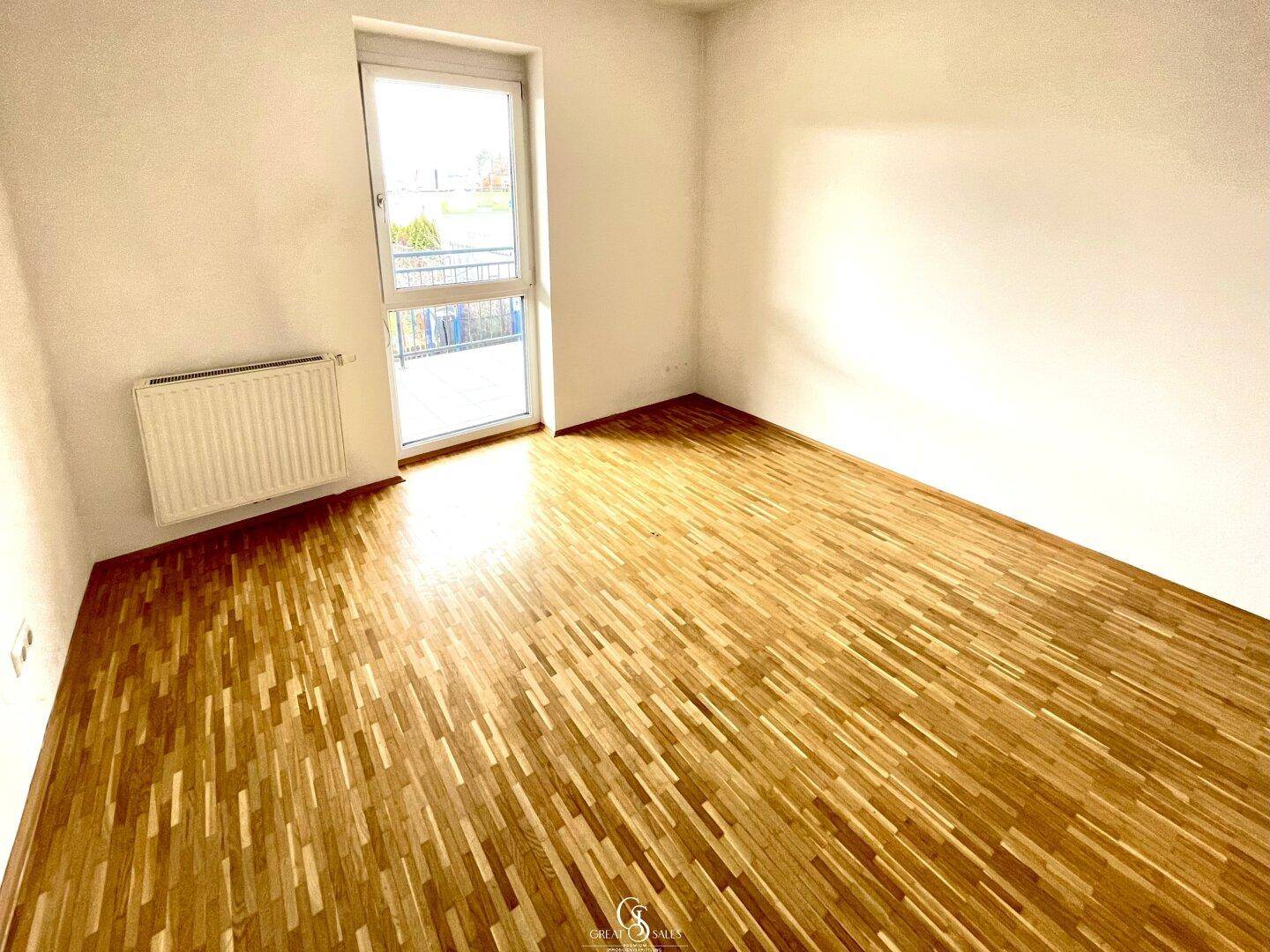 Schlafzimmer mit Parkettboden und Fenster, das einen Blick auf die Umgebung ermöglicht.