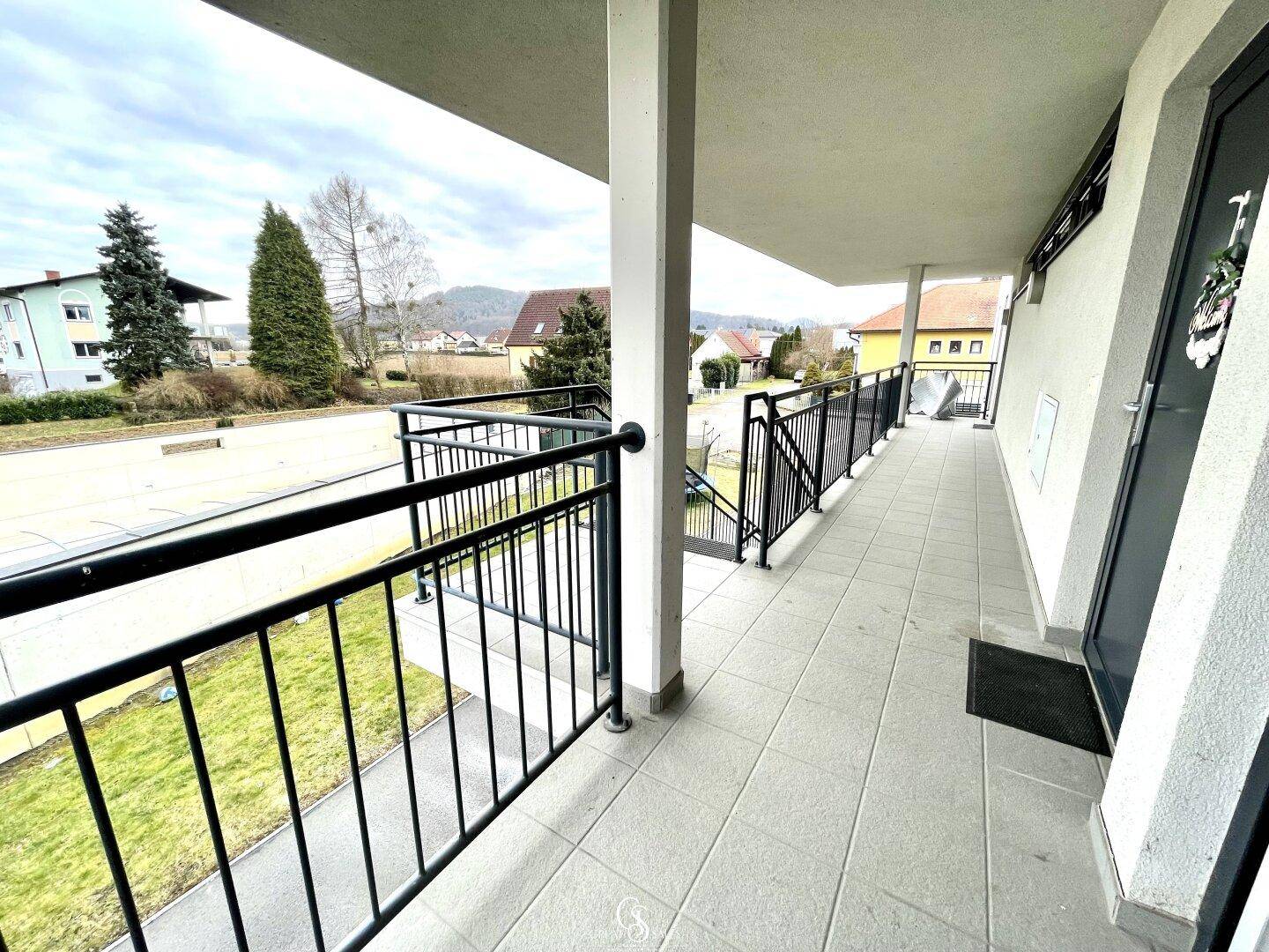 Überdachter Balkon mit Fliesenboden und Blick auf die Straße und die umliegende Landschaft.