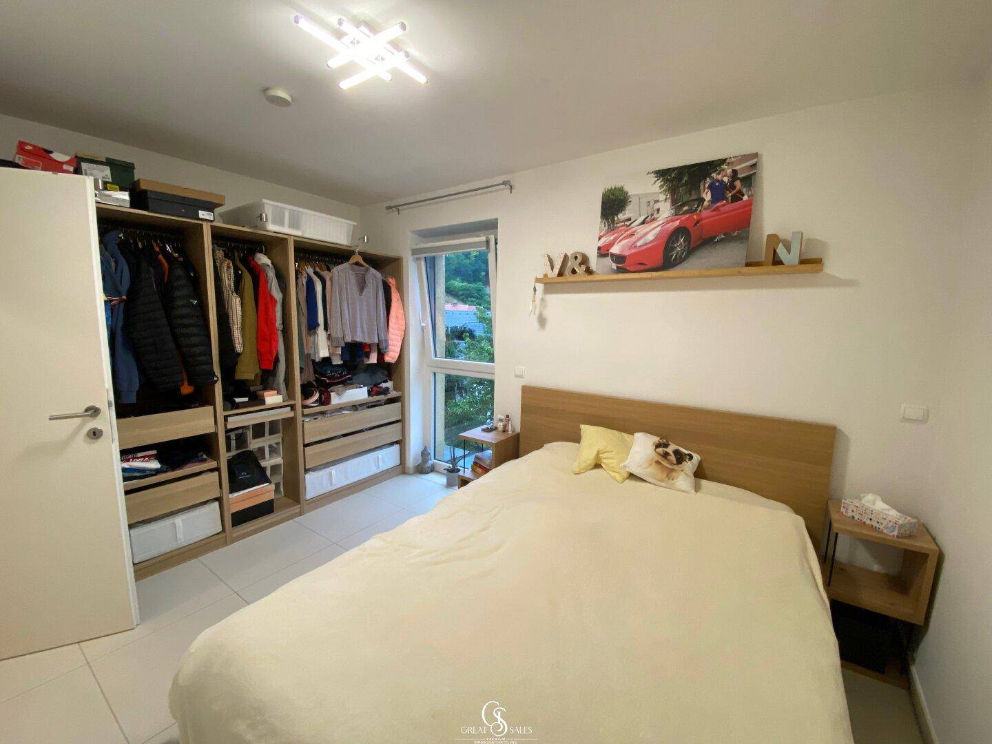 Schlafzimmer mit großem Doppelbett, offenem Kleiderschrank und Blick ins Grüne.