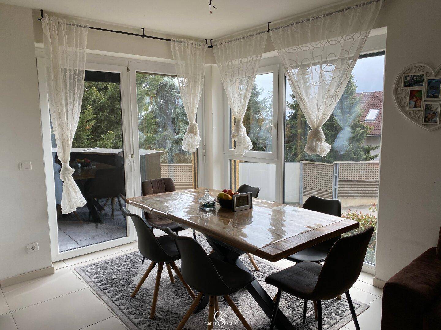 Heller Essbereich mit Holztisch, modernen Stühlen und Zugang zu einem Balkon.