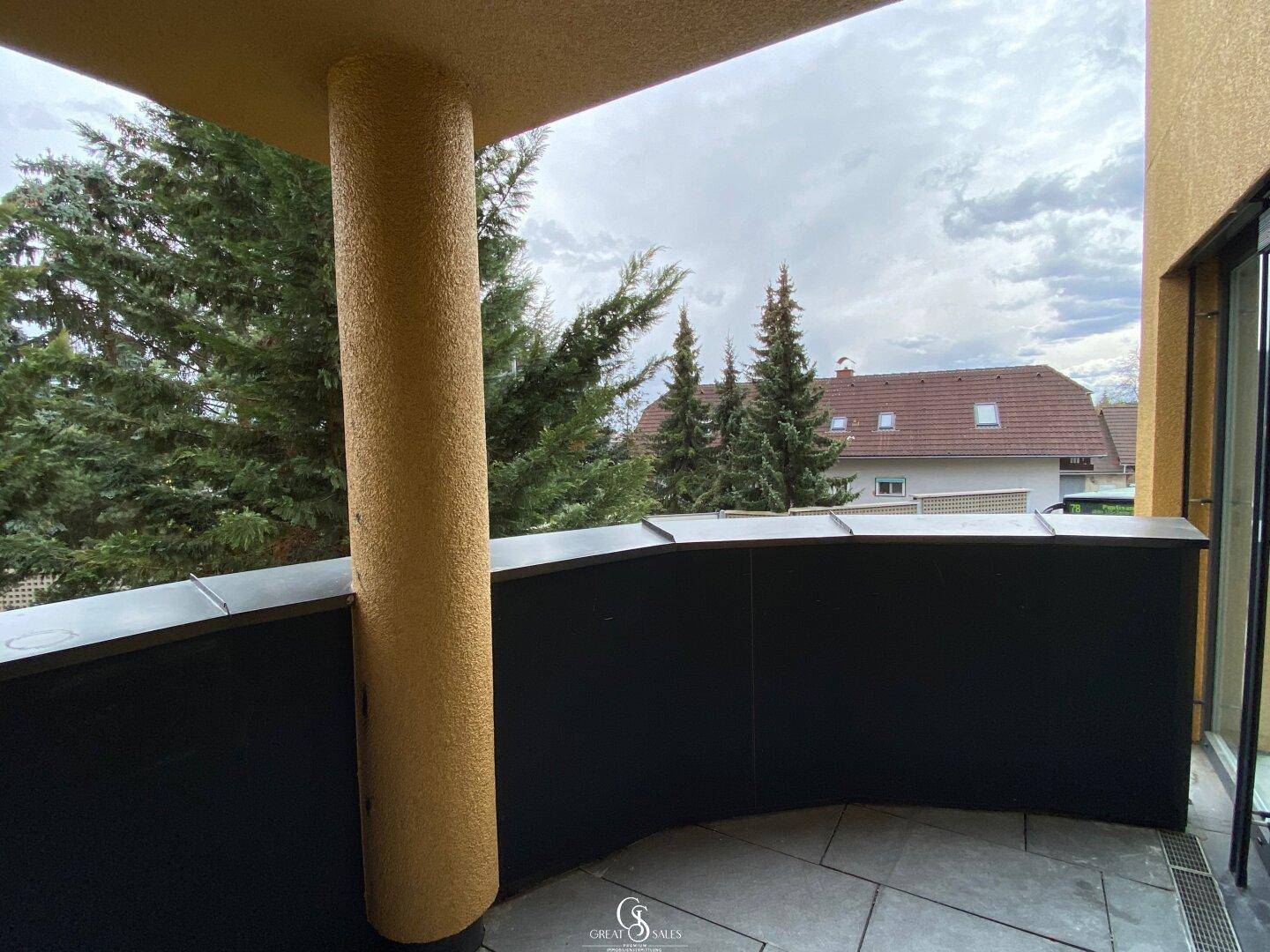 Runder Balkon mit Fliesenboden und seitlichem Blick auf die umliegende Wohnbebauung.