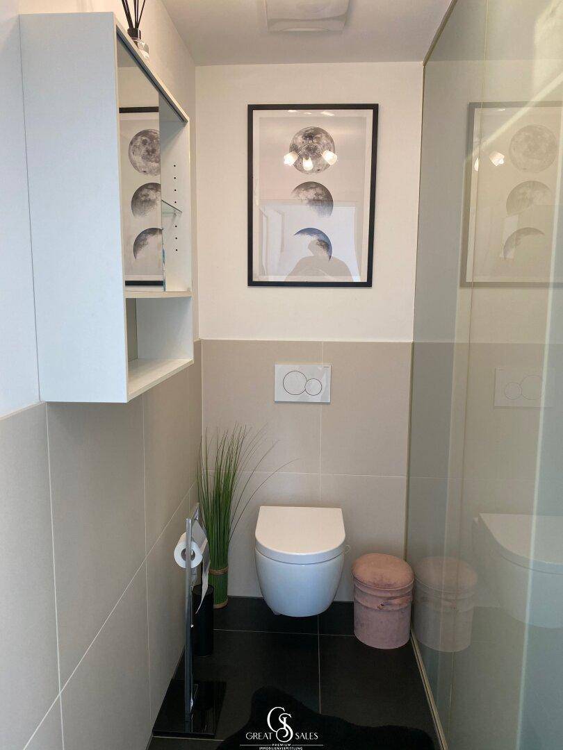 Modernes Gäste-WC mit wandmontierter Toilette und stilvoller Dekoration.