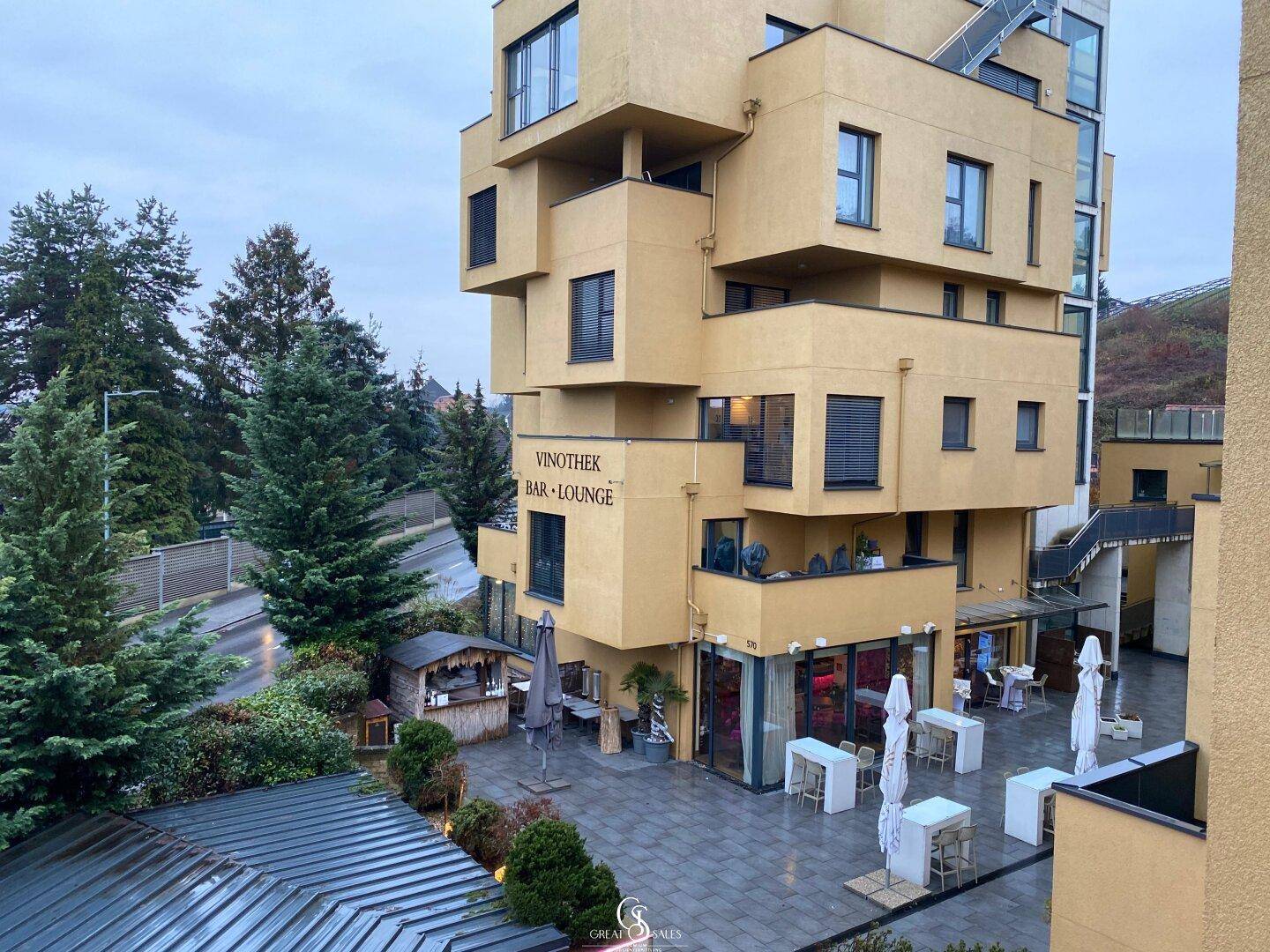 Außenbereich mit möblierter Terrasse und Blick auf die moderne Architektur des Gebäudes.