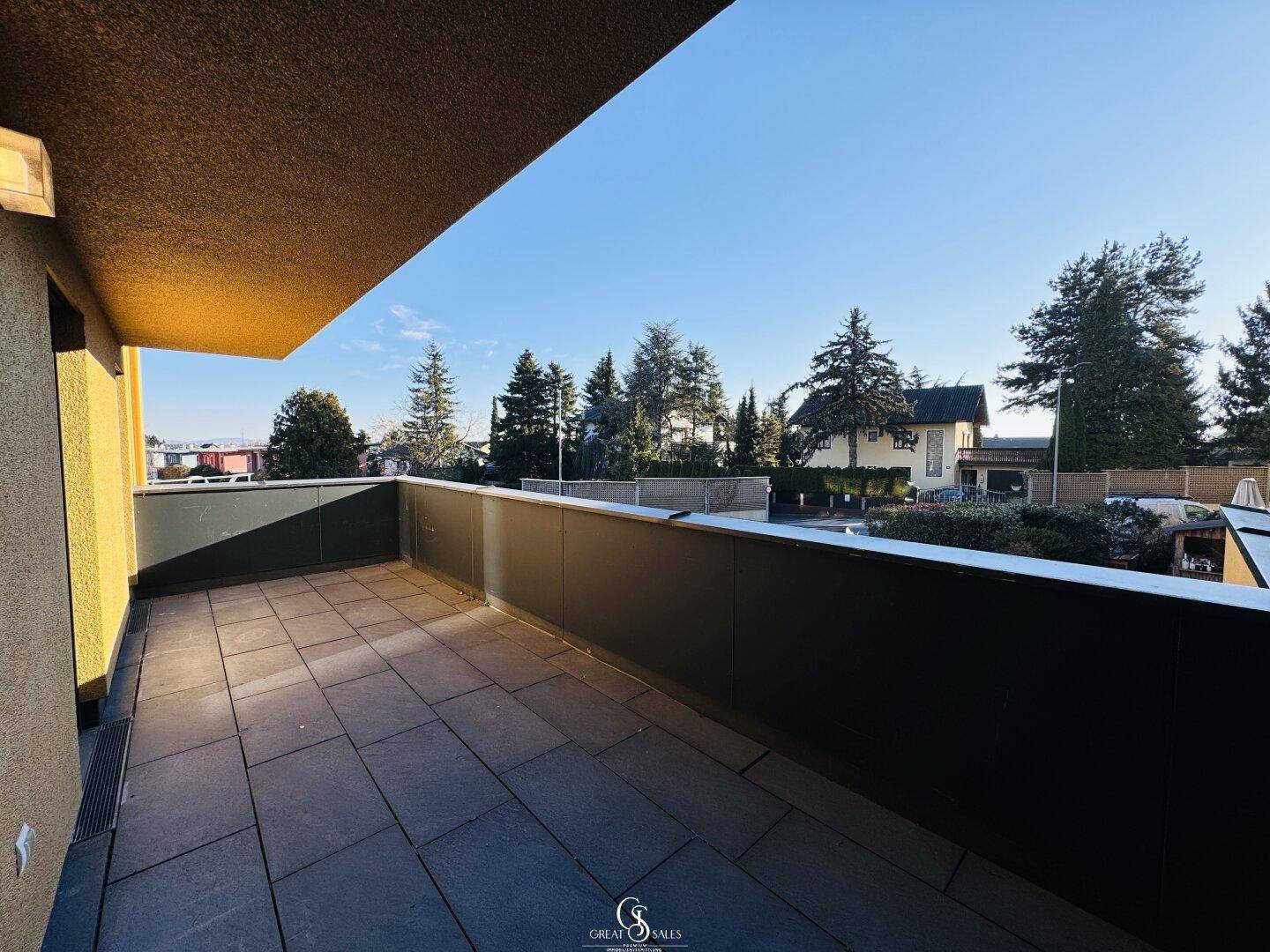 Geräumiger Balkon mit Fliesenboden und Blick auf die umliegende grüne Landschaft.