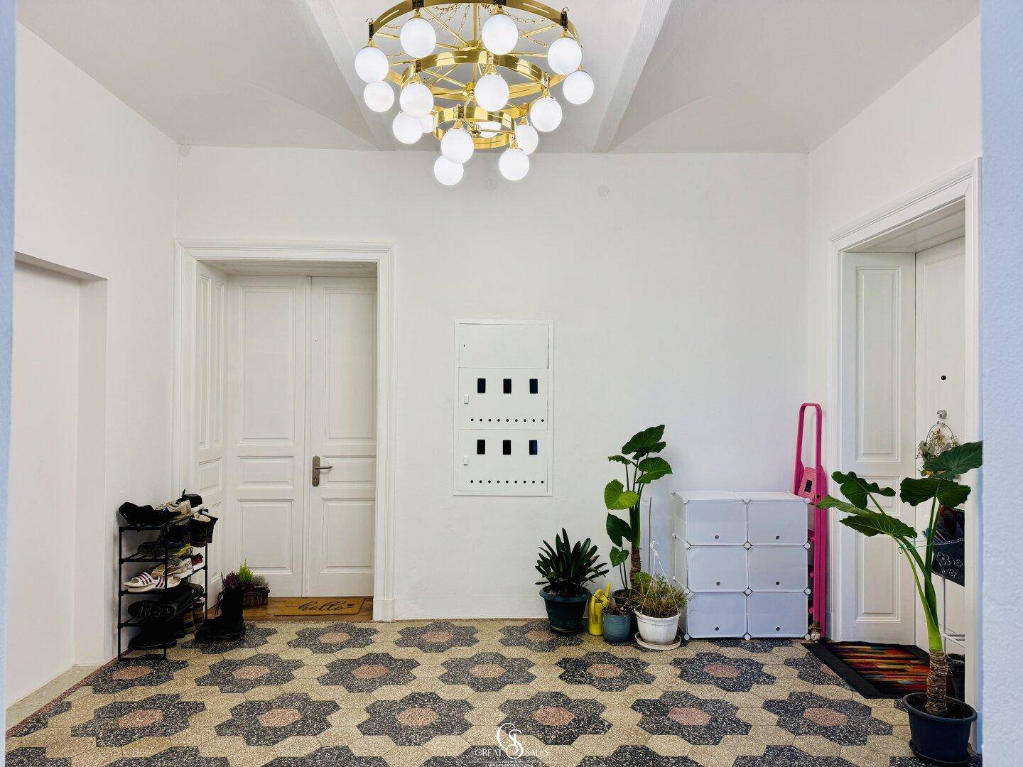 Geräumiger Flur mit auffälligem Fliesenboden, hohen Decken und moderner Deckenleuchte.