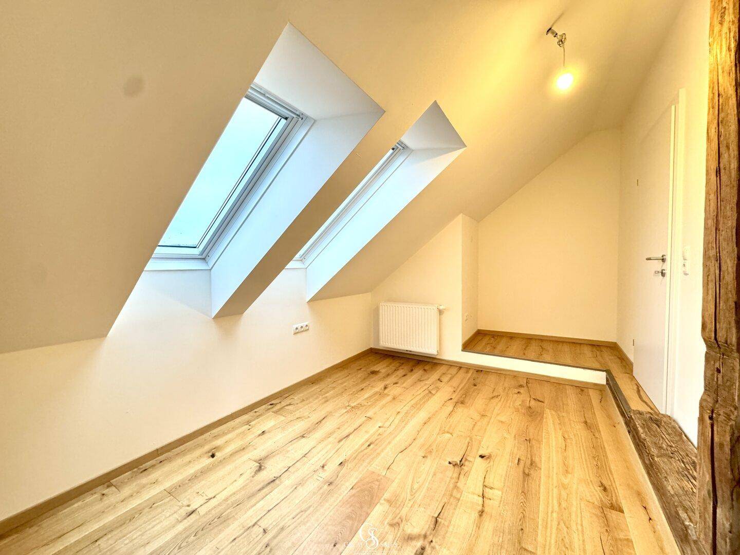 Gemütlicher Dachgeschossraum mit Dachschrägen und zwei Dachfenstern, ideal als Schlaf- oder Arbeitszimmer.