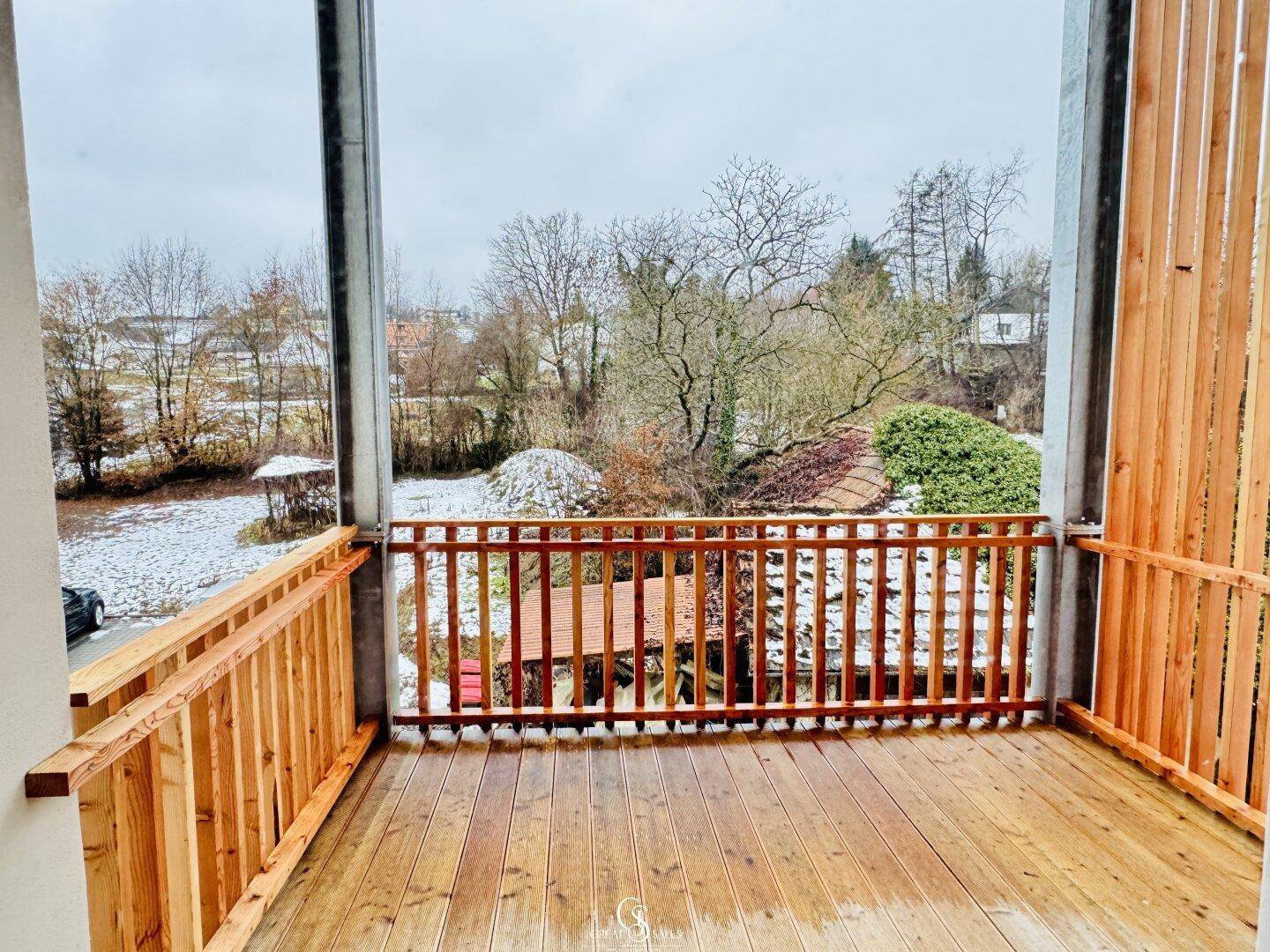 Geräumiger Holzbalkon mit Blick auf die verschneite Landschaft und umliegende Natur.