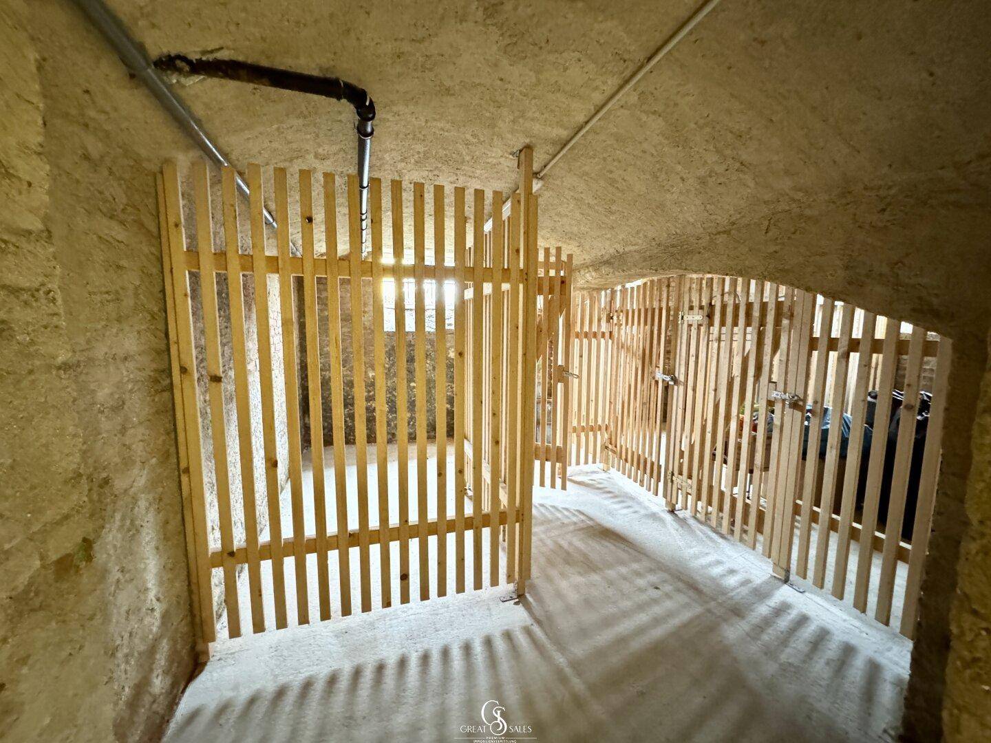 Abgetrennte Kellerabteile mit Holzlattenwänden, bieten individuellen Stauraum für Bewohner.