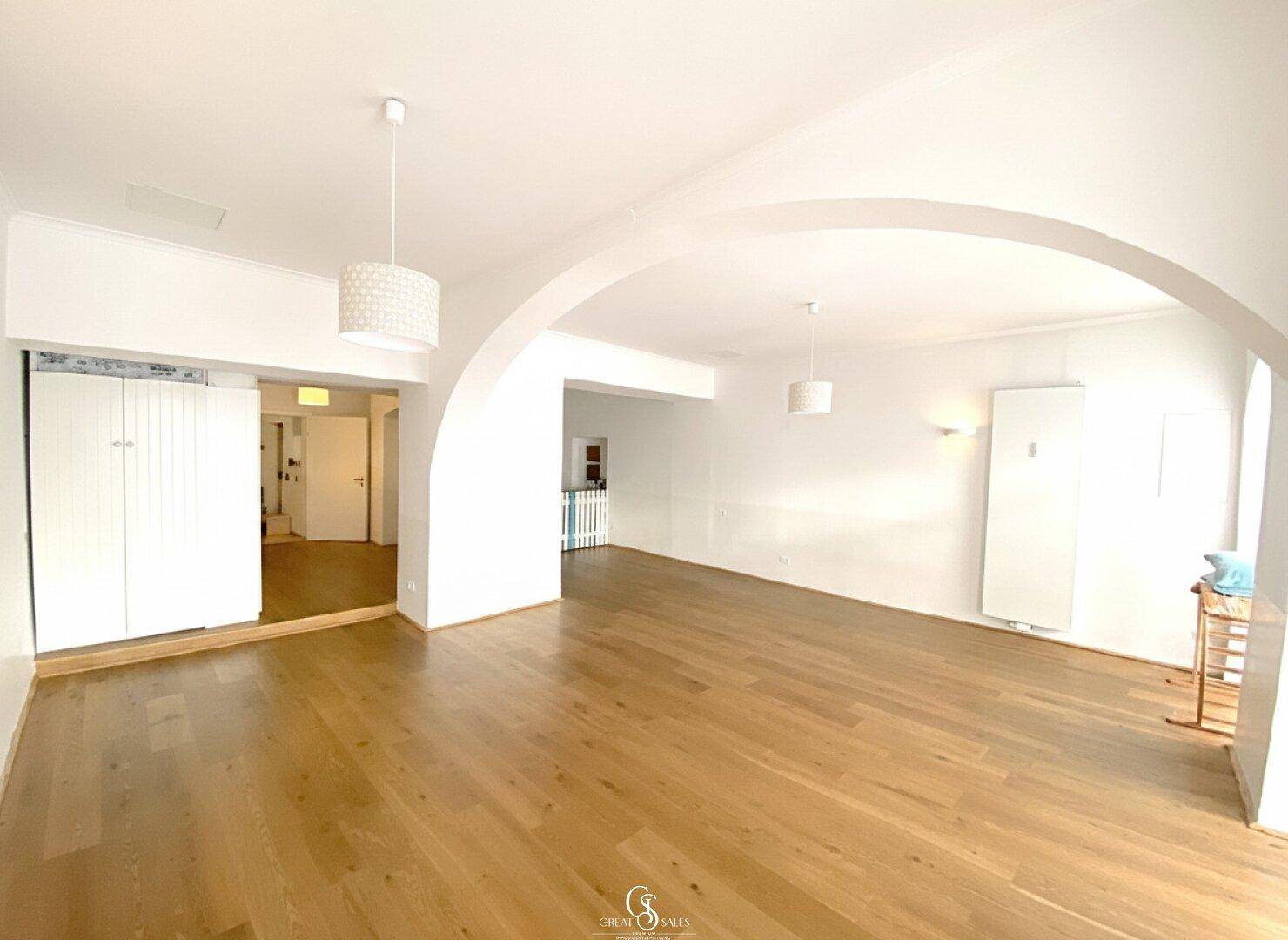 Großer, heller Raum mit Holzboden und eleganten Rundbögen, ideal für vielfältige Nutzung.
