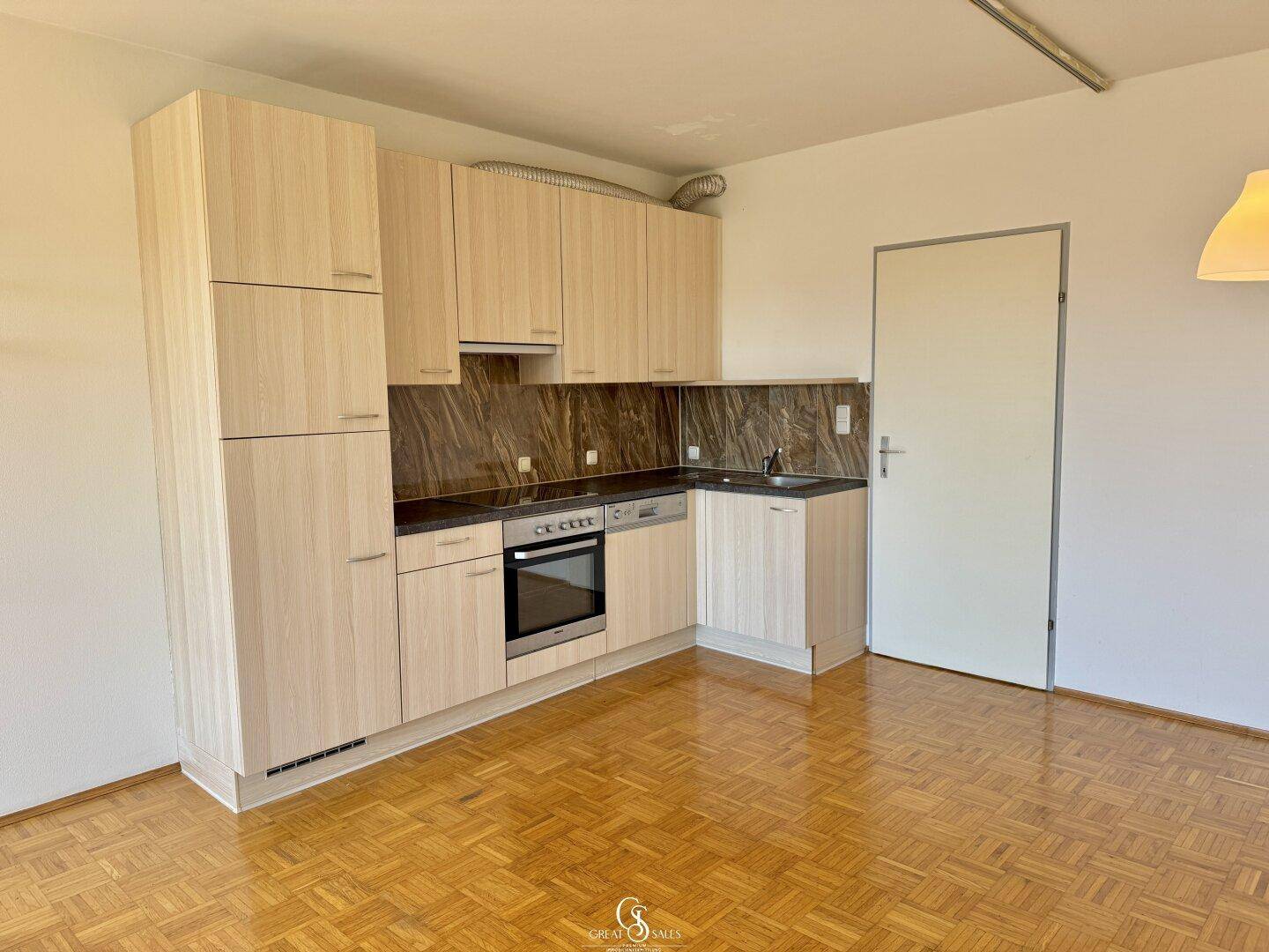 Funktionale Küchenzeile mit hellen Holzschränken und integrierten Geräten, ideal für kleine Haushalte.