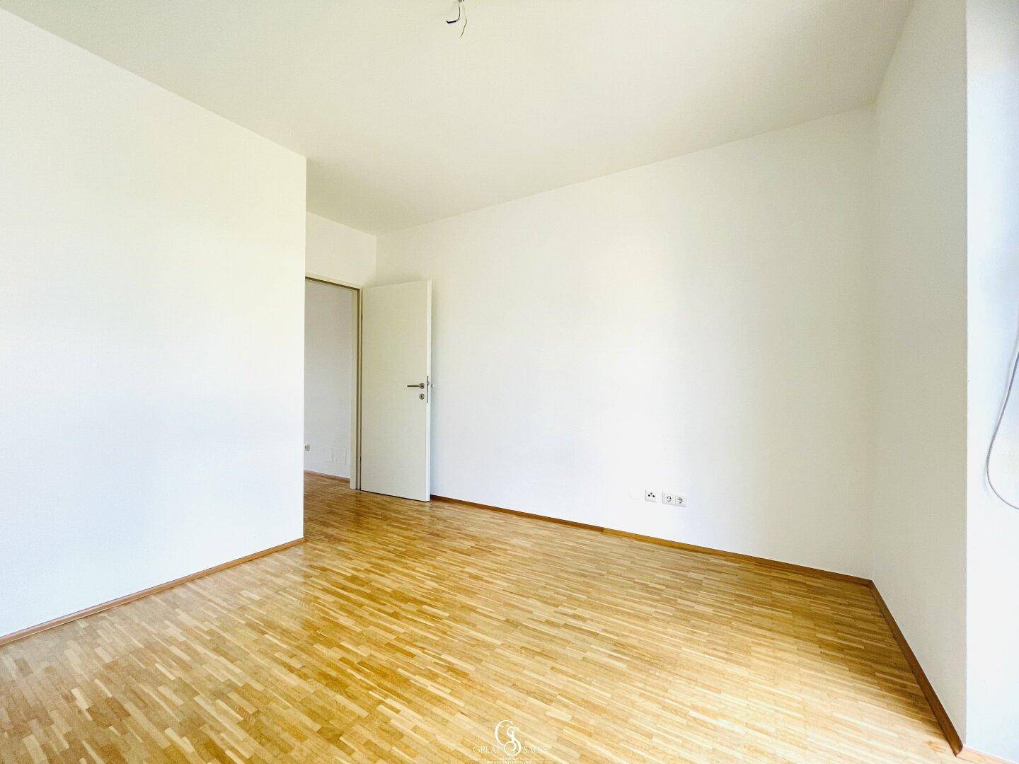 Geräumiges Schlafzimmer mit Parkettboden und weiß gestrichenen Wänden, bereit zum Einrichten.