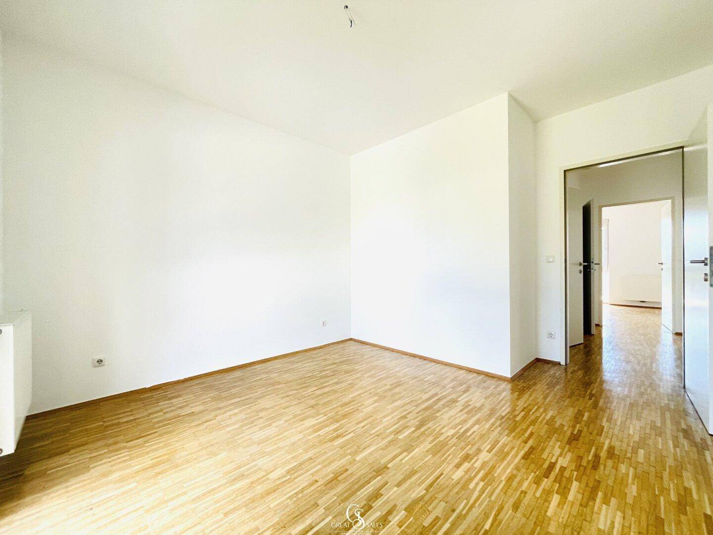 Helles Schlafzimmer mit Parkettboden und Zugang zu weiteren Räumen der Wohnung.