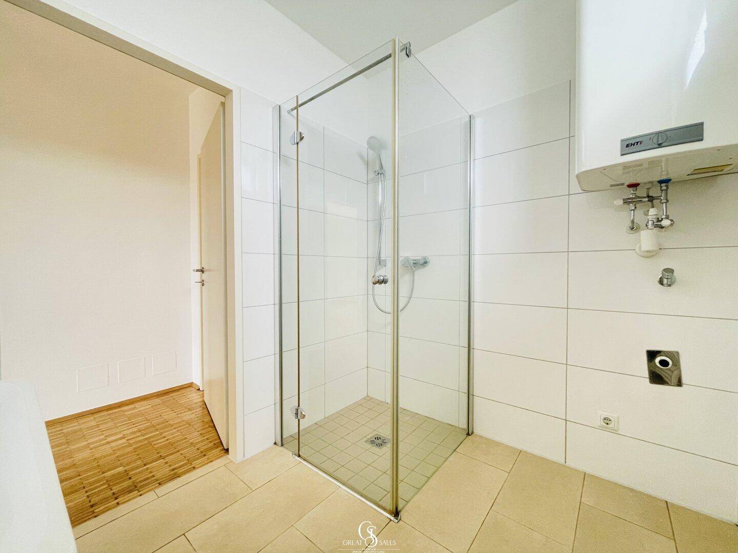 Helles Badezimmer mit geräumiger Duschkabine und weiß gefliesten Wänden.