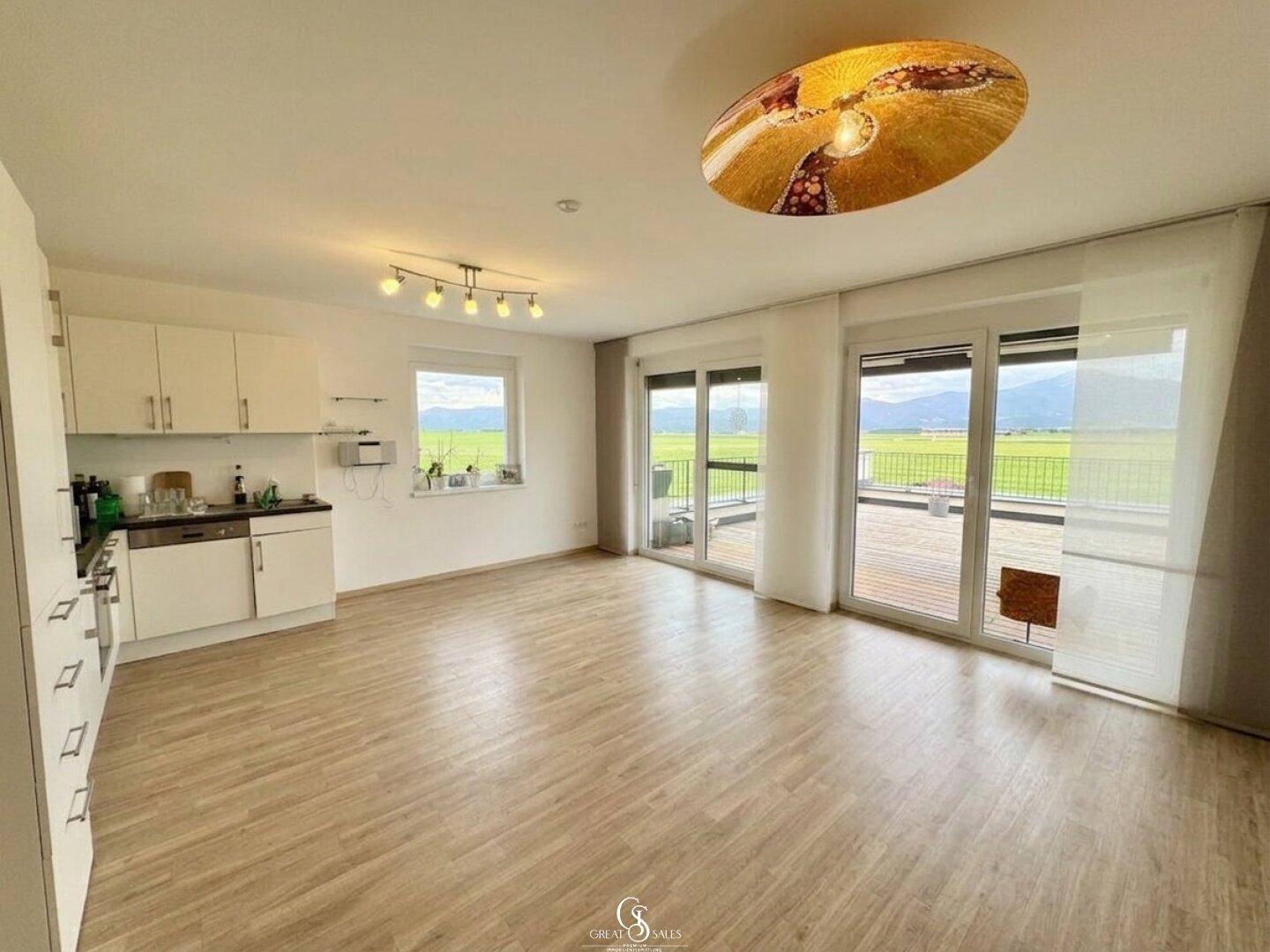 Offener Küchen- und Wohnbereich mit einfacher Küchenzeile und Zugang zur Terrasse mit Aussicht.