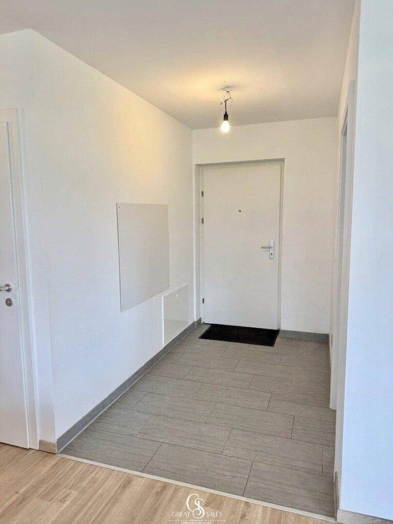 Eingangsbereich mit hellen Fliesen, weiß gestrichenen Wänden und der Haupttür zur Wohnung.