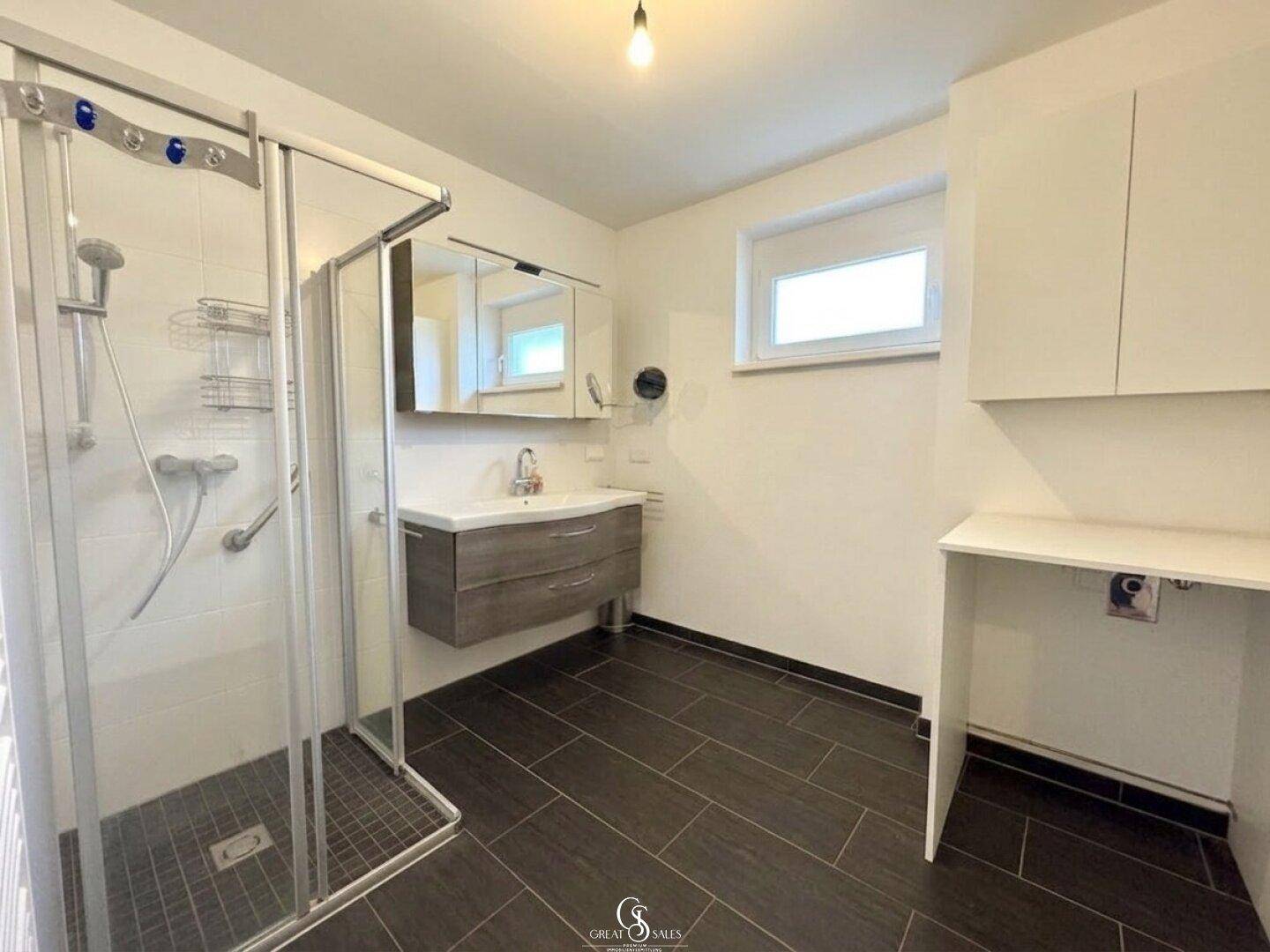 Modernes Badezimmer mit Duschkabine, schwebendem Waschtisch, Spiegelschrank und Fenster.