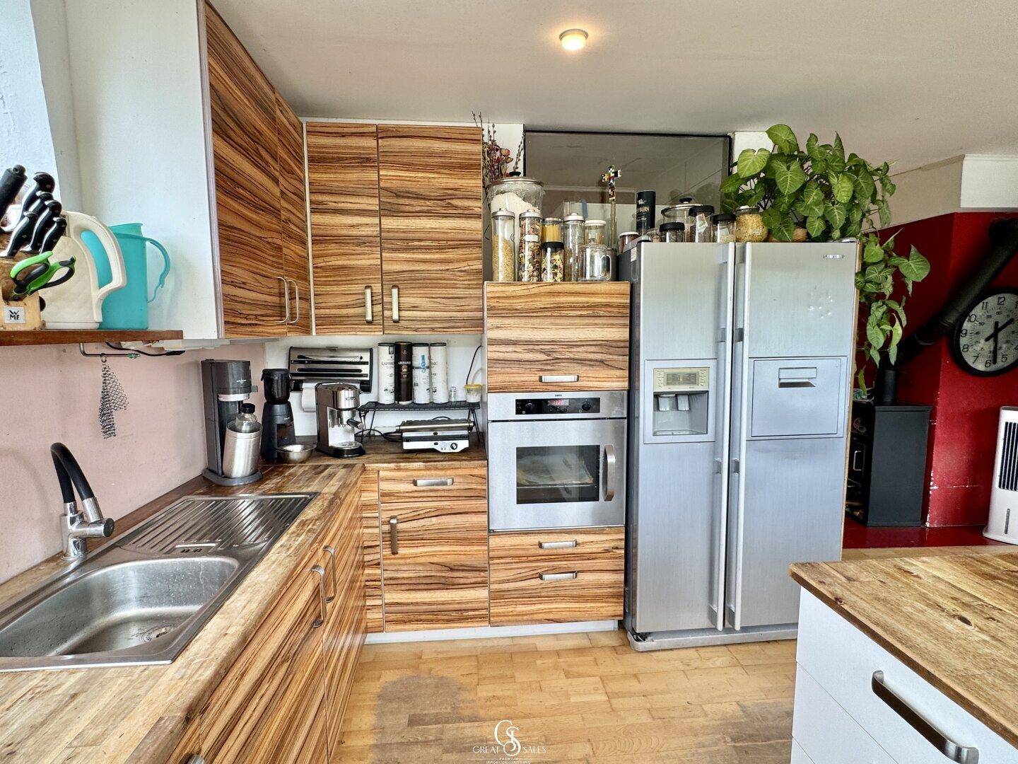Küche mit Holzfronten, integriertem Backofen und großem Kühlschrank.