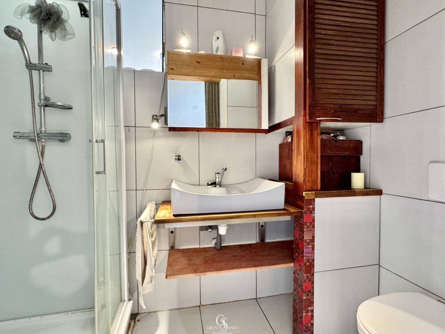 Modernes Badezimmer mit Duschkabine, Waschbecken und weißen Fliesen.