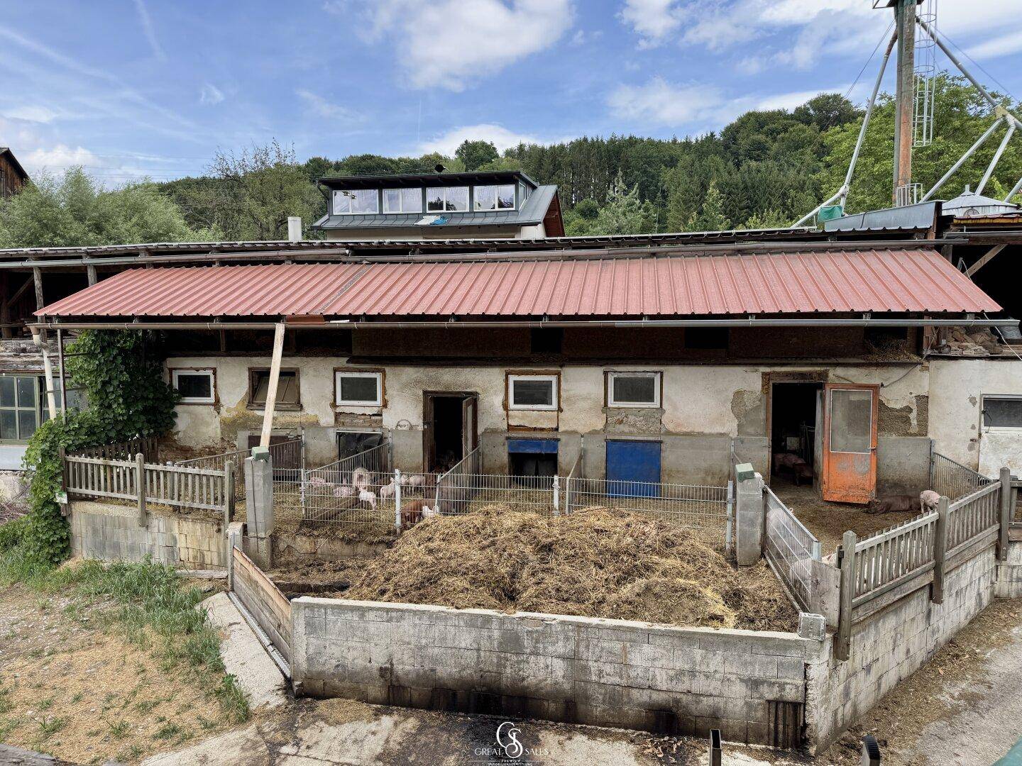 Landwirtschaftliche Gebäude mit einem Tiergehege und Misthaufen.