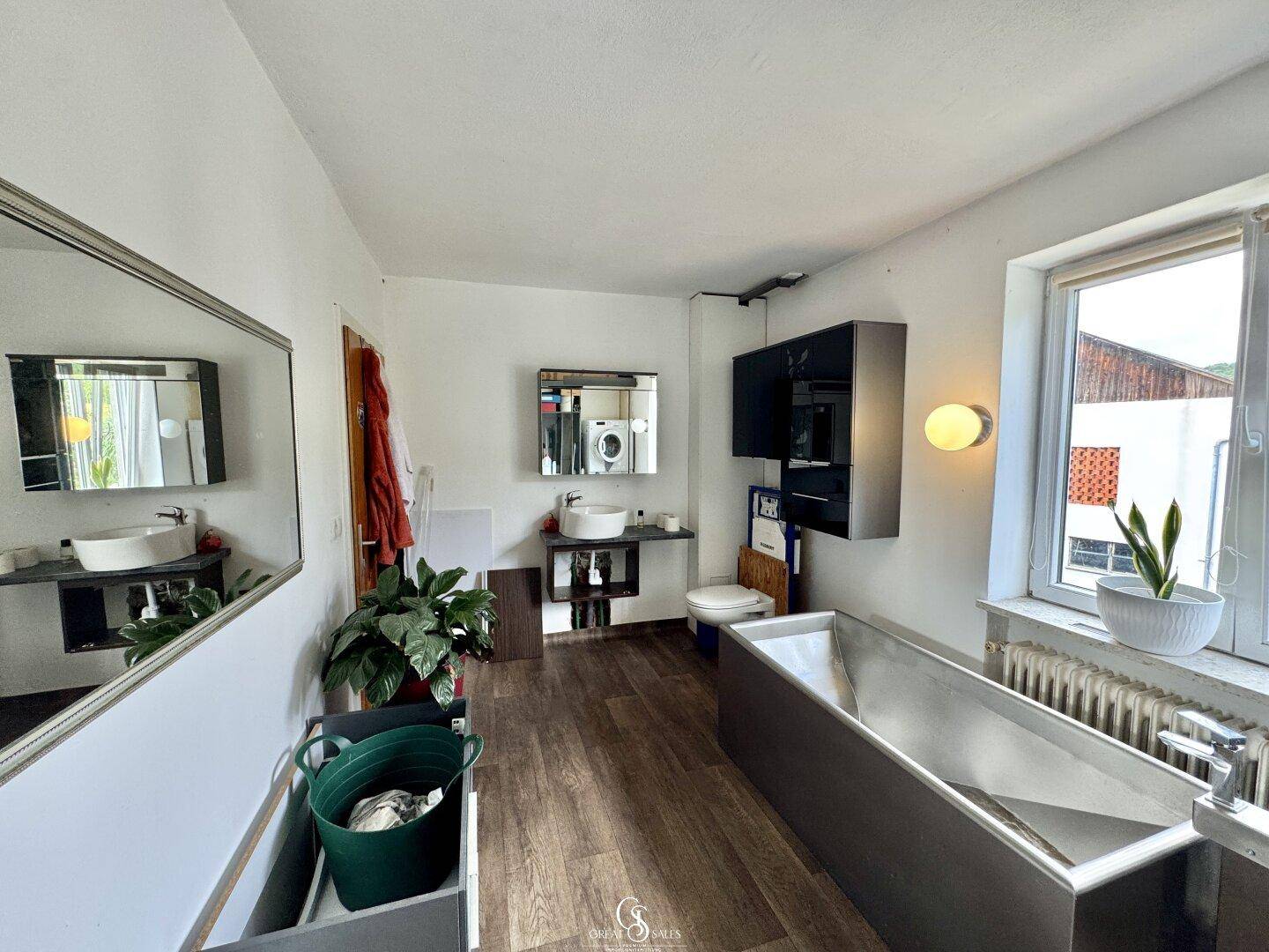 Modernes Badezimmer mit freistehender Badewanne, Waschbecken und Fenster.
