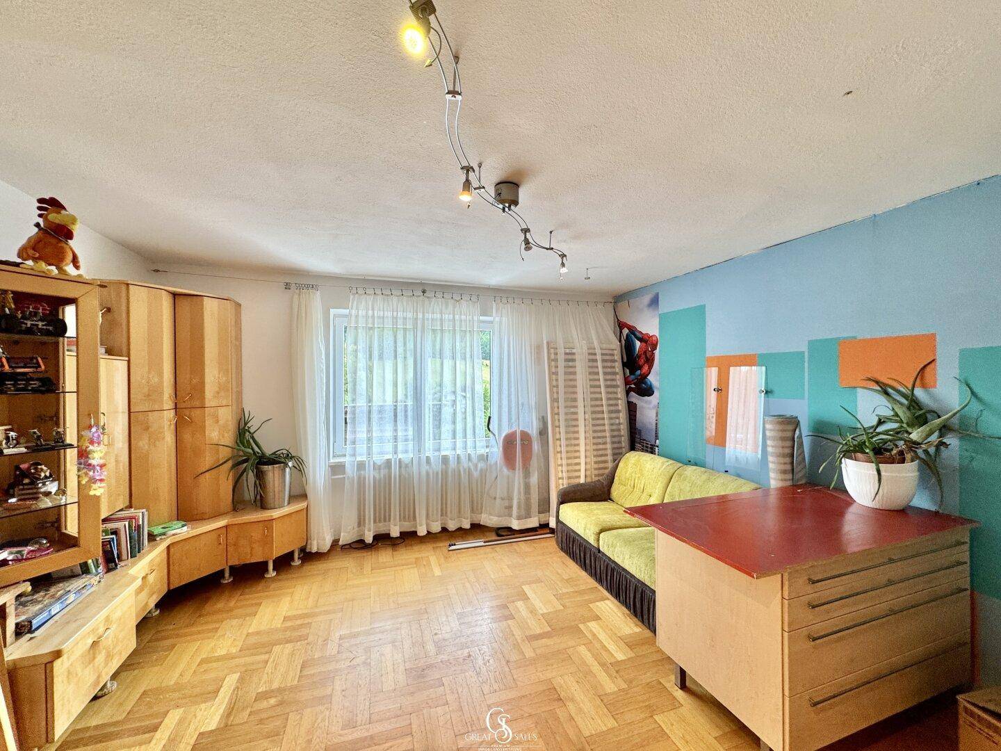 Helles Wohnzimmer mit Fischgrätparkett, blauer Wand und Holzmöbeln.