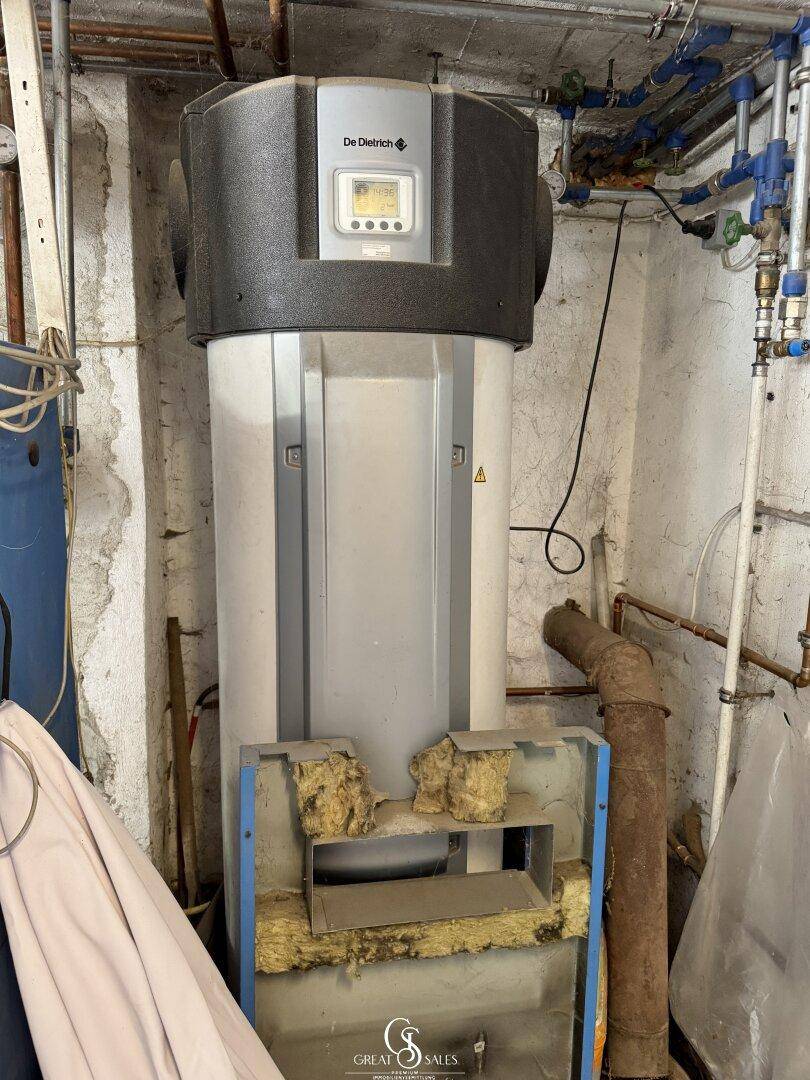 Heizungsraum mit Warmwasserspeicher und sichtbaren Rohrleitungen.