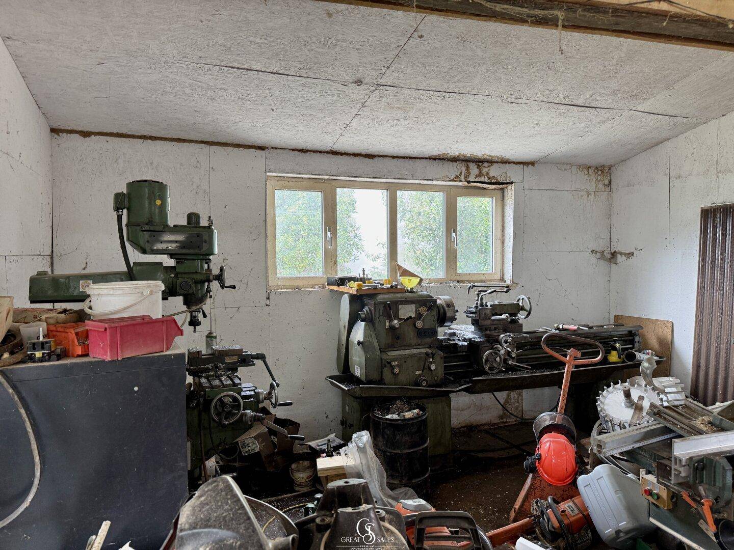 Werkstattraum mit verschiedenen Maschinen, Werkzeugen und Fenstern.
