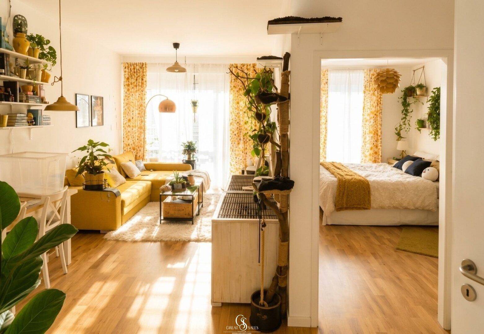 Helles Wohnzimmer mit gelbem Sofa, Holzboden und offenem Übergang zum Schlafzimmer.