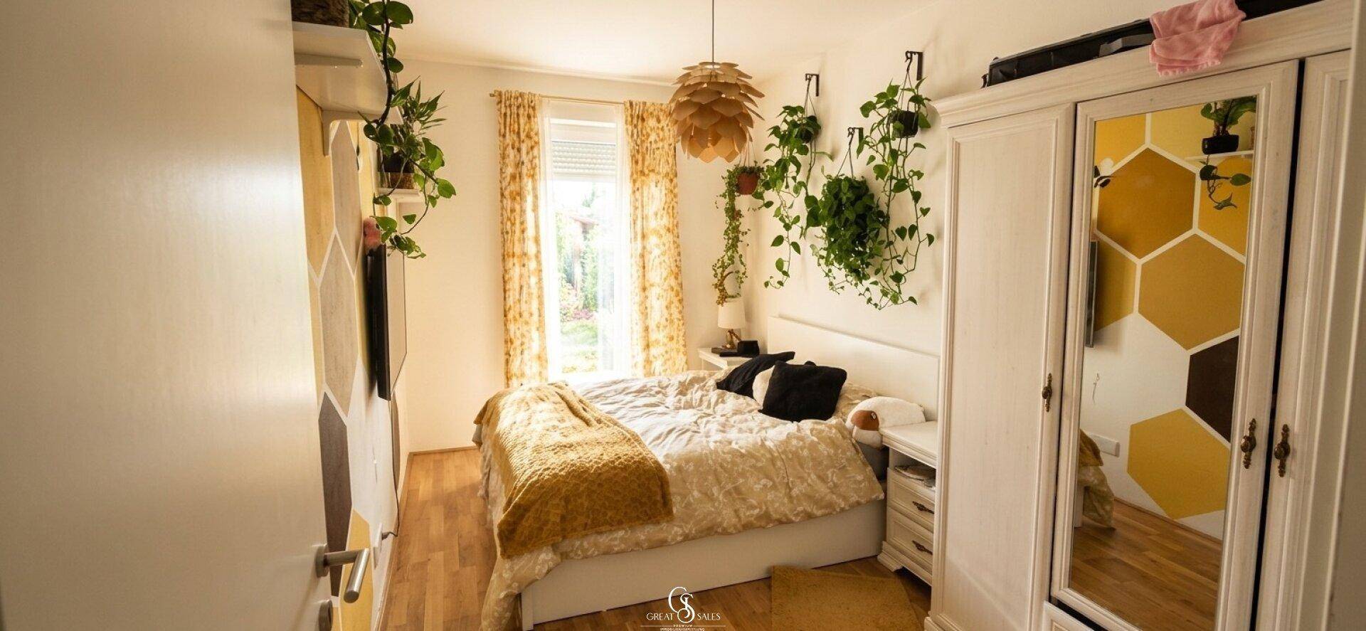 Helles Schlafzimmer mit Doppelbett, Holzboden und kreativer Wandgestaltung in Gelbtönen.