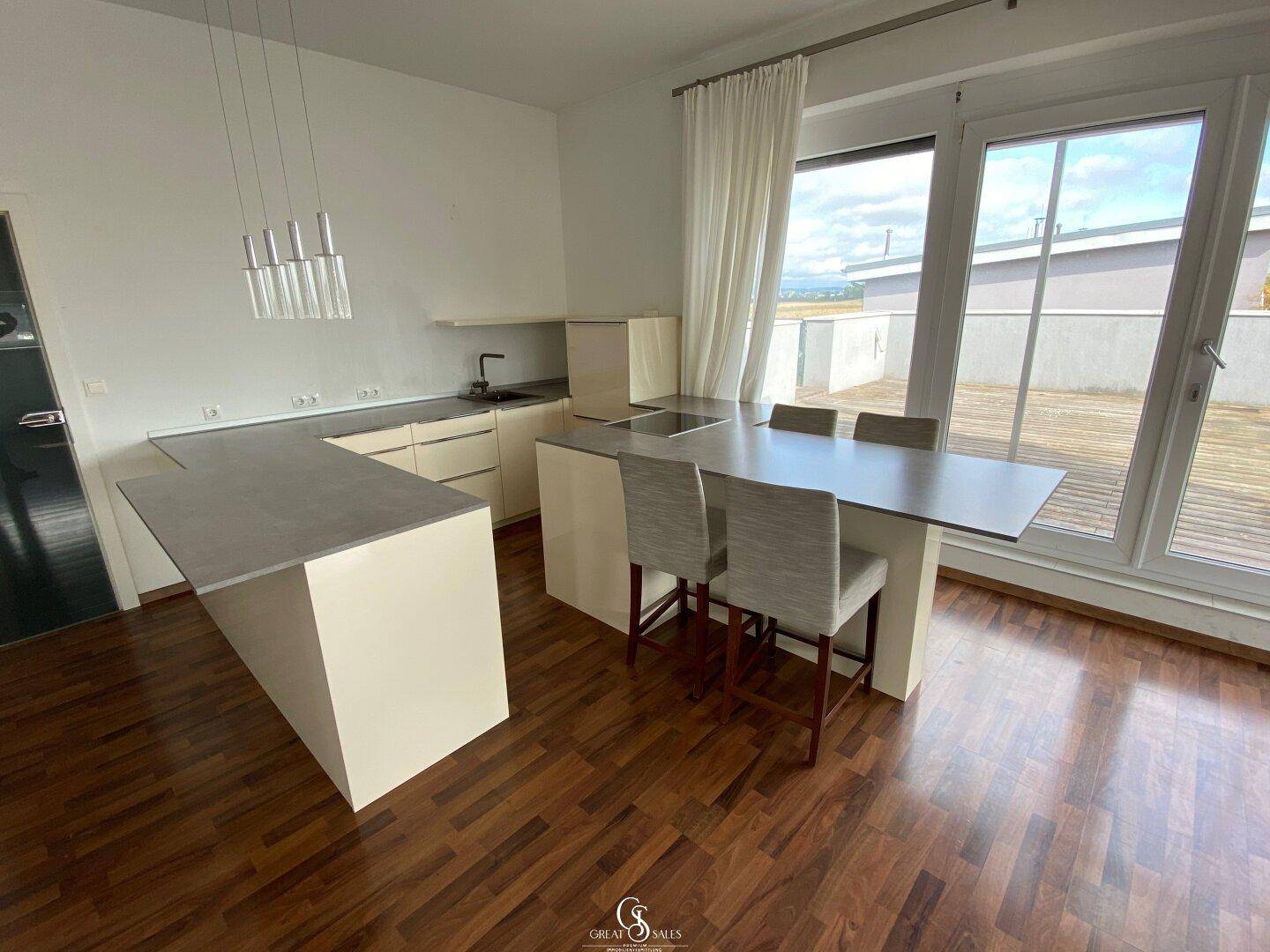 Moderne Küche mit Kochinsel, integriertem Essbereich und direktem Zugang zur Terrasse.