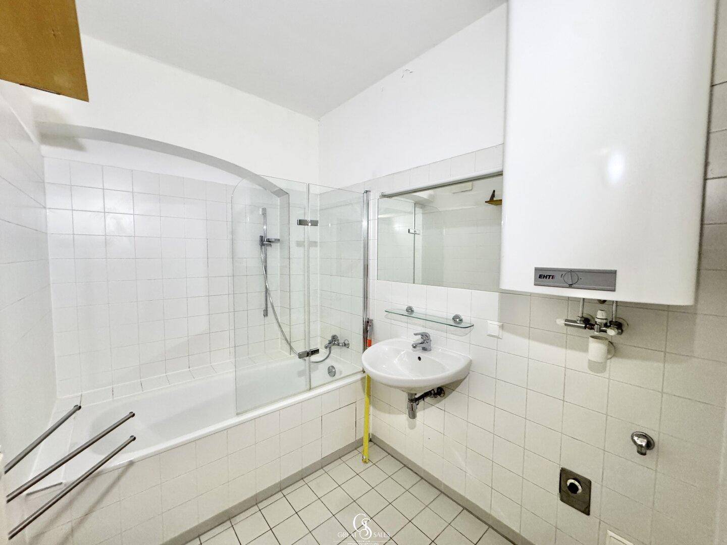 Badezimmer mit Badewanne, Duschabtrennung, Waschbecken und weiß gefliesten Wänden.