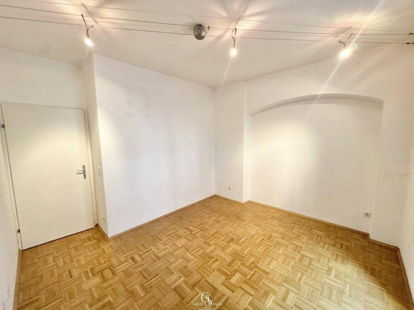 Leeres Schlafzimmer mit Parkettboden und einer eleganten Bogennische, ideal für Dekoration.