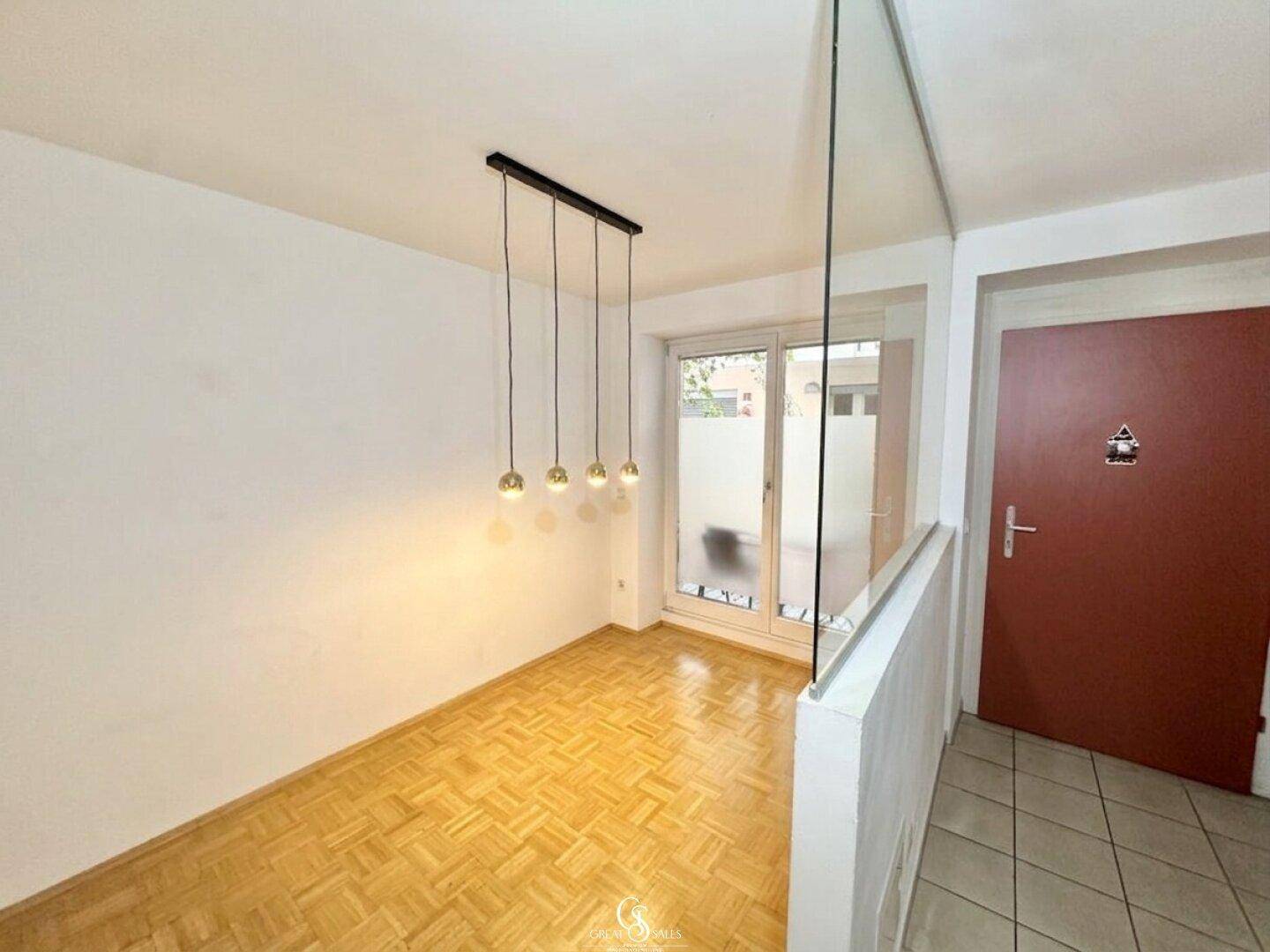 Heller Wohnraum mit Parkettboden, modernen Hängelampen und Zugang zur Terrasse.