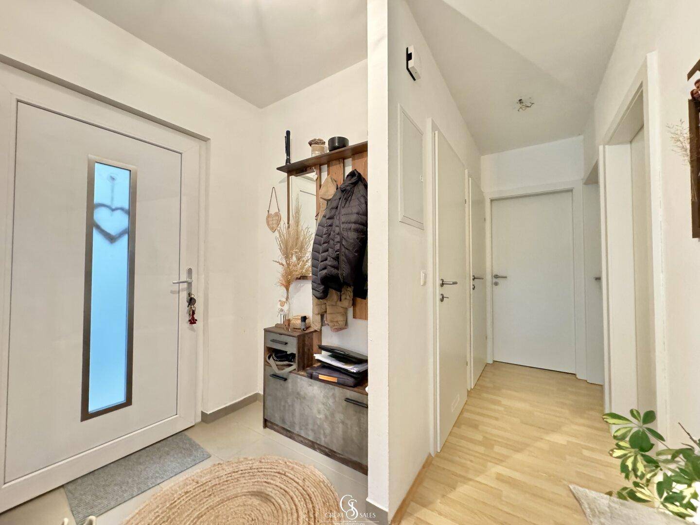 Heller Eingangsbereich mit Garderobe und Holzboden, führt zu weiteren Räumen.