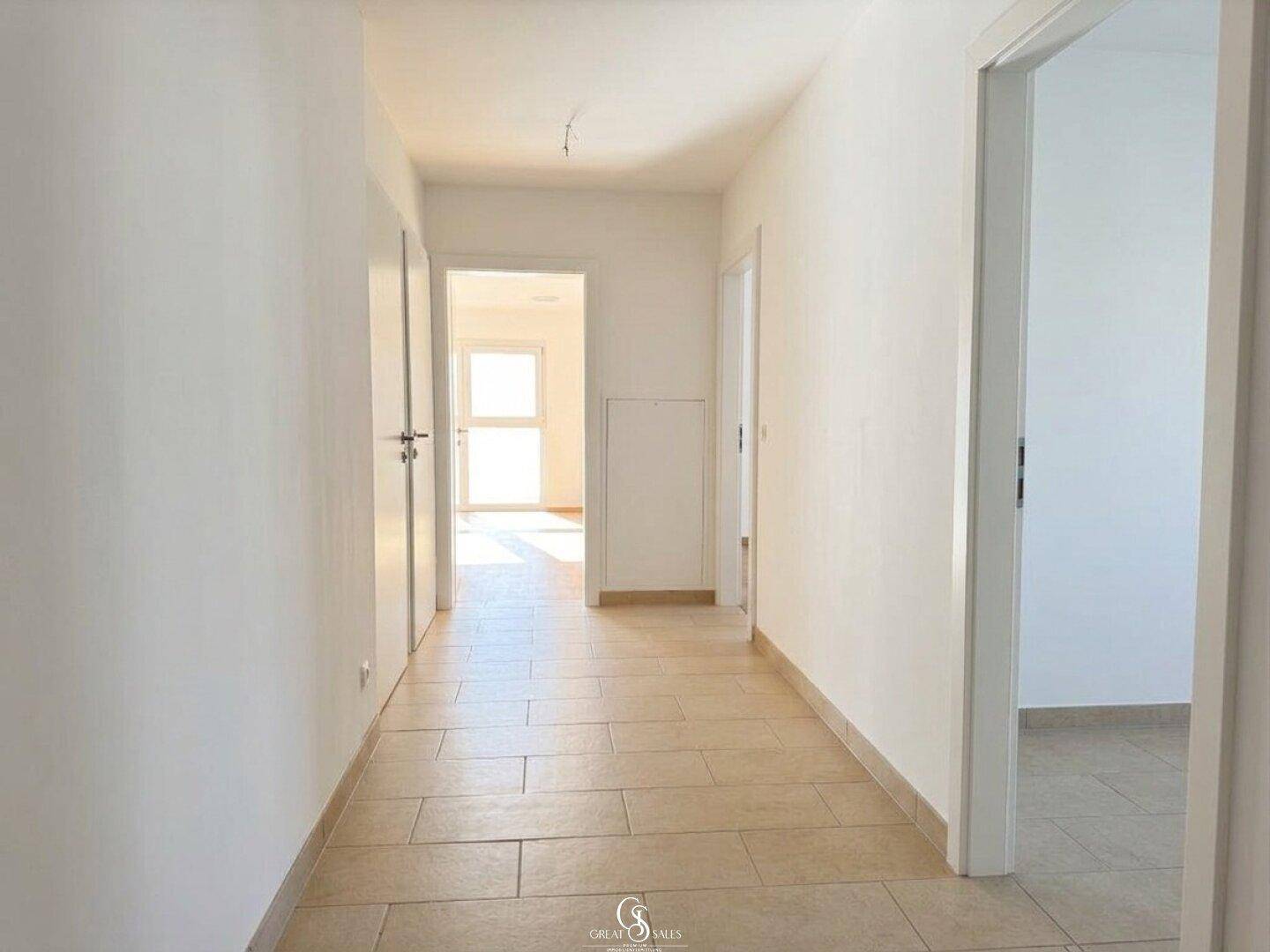 Heller Flur mit beigefarbenen Fliesen, der zu verschiedenen Räumen der Wohnung führt und einladend wirkt.