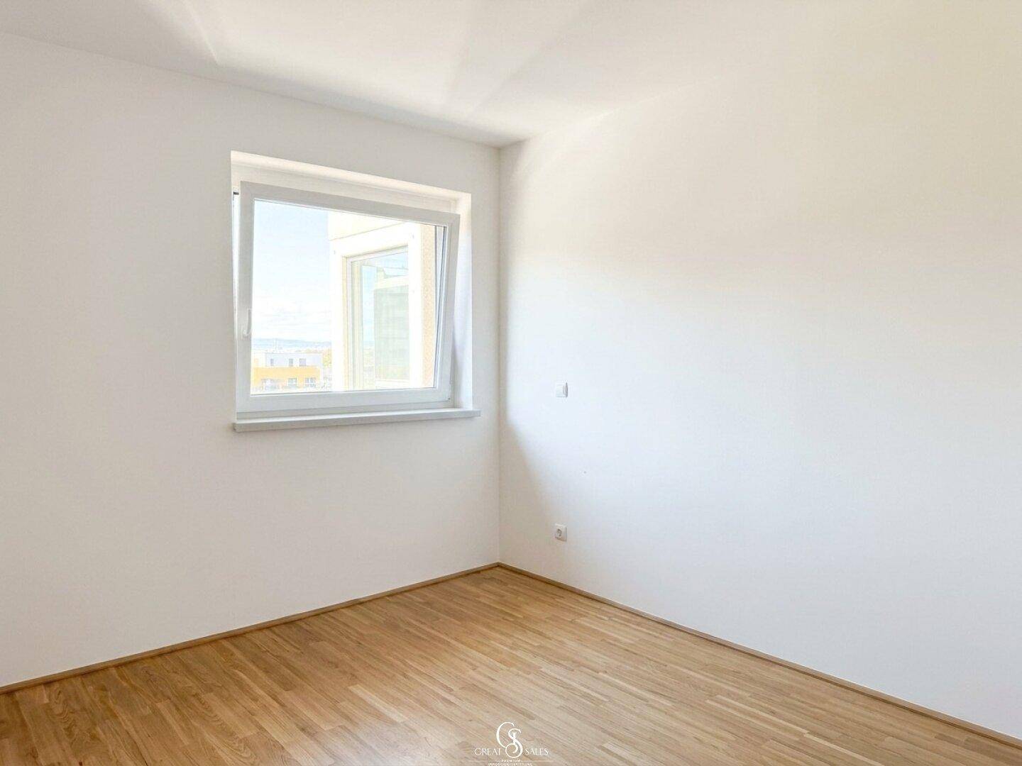 Geräumiges Schlafzimmer mit Holzboden und einem Fenster, das einen weiten Blick in die Umgebung ermöglicht.