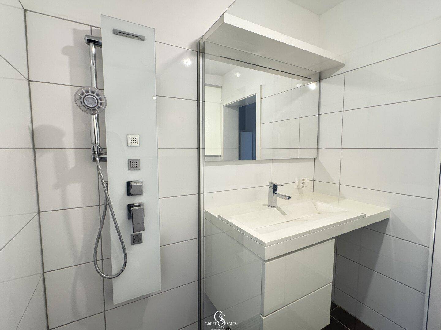Detailansicht der modernen Dusche mit Duschpaneel und dem eleganten Waschtisch im Badezimmer.