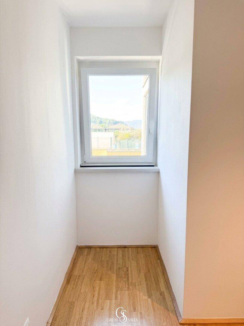 Kleiner Raum mit Fenster und Holzboden, der als Abstellraum oder begehbarer Kleiderschrank dienen könnte.