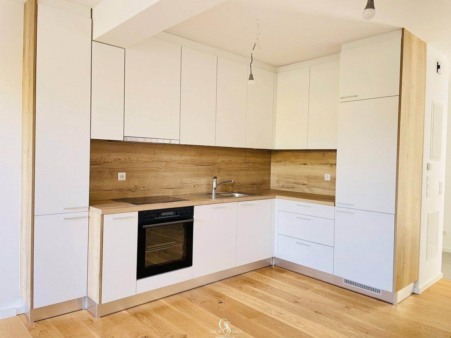 Moderne Einbauküche mit weißen Fronten, Holzdetails und integrierten Geräten.