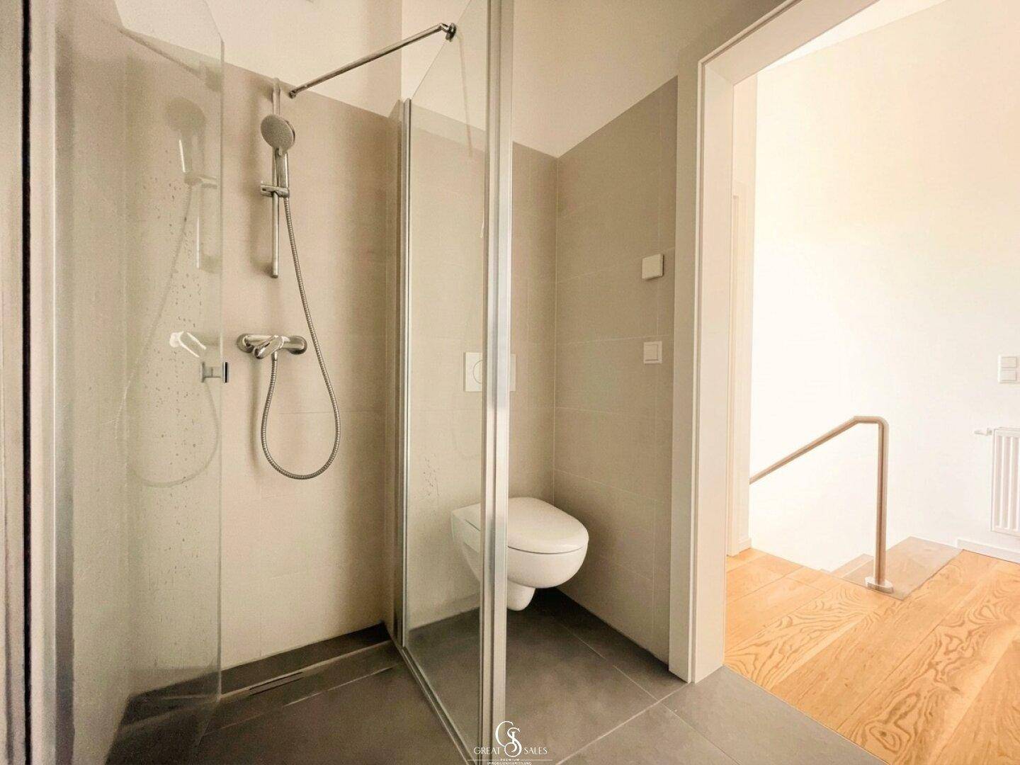 Modernes Badezimmer mit ebenerdiger Dusche, Wand-WC und dunklen Bodenfliesen.